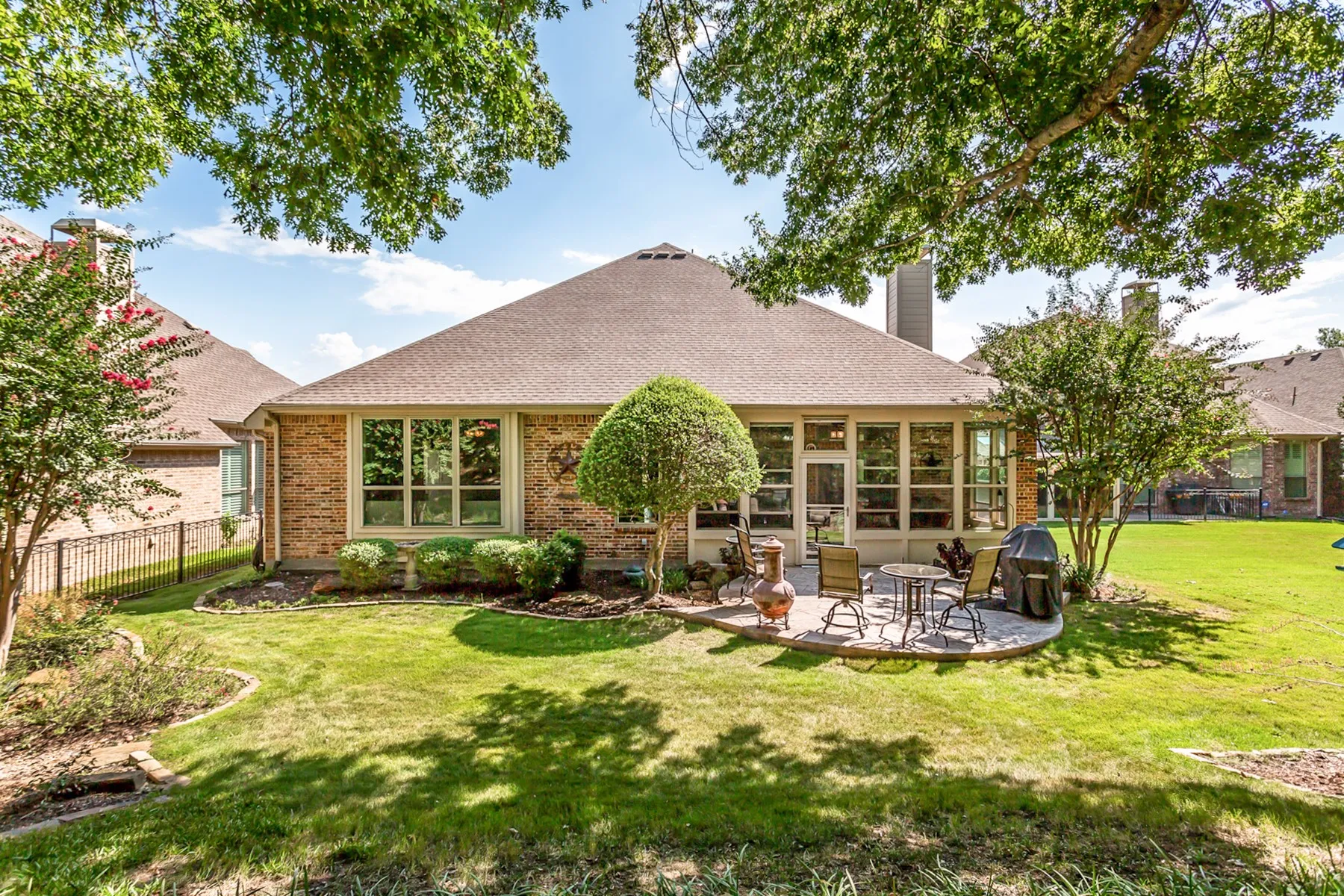Expansive backyard with a manicured lawn, brick exterior, and a built-in patio
