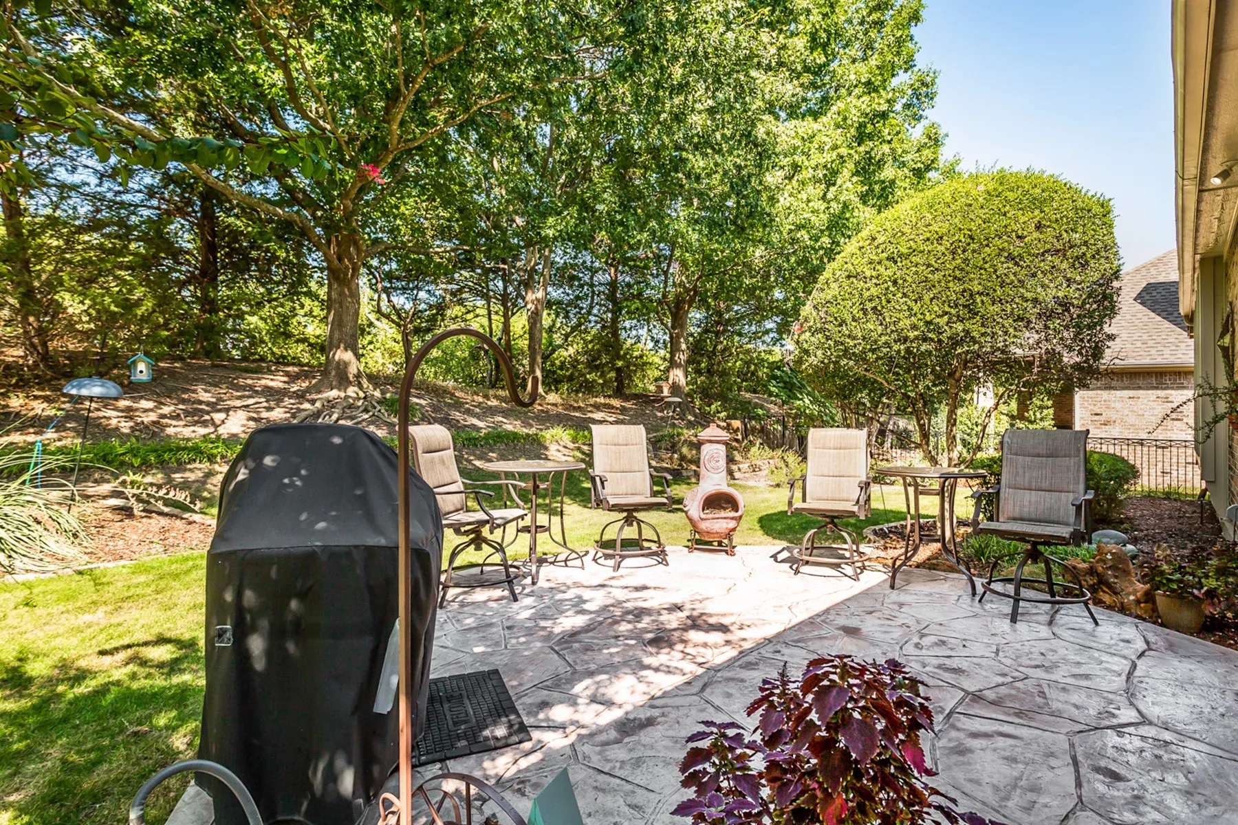 Stamped concrete patio with a landscaped perimeter and mature trees