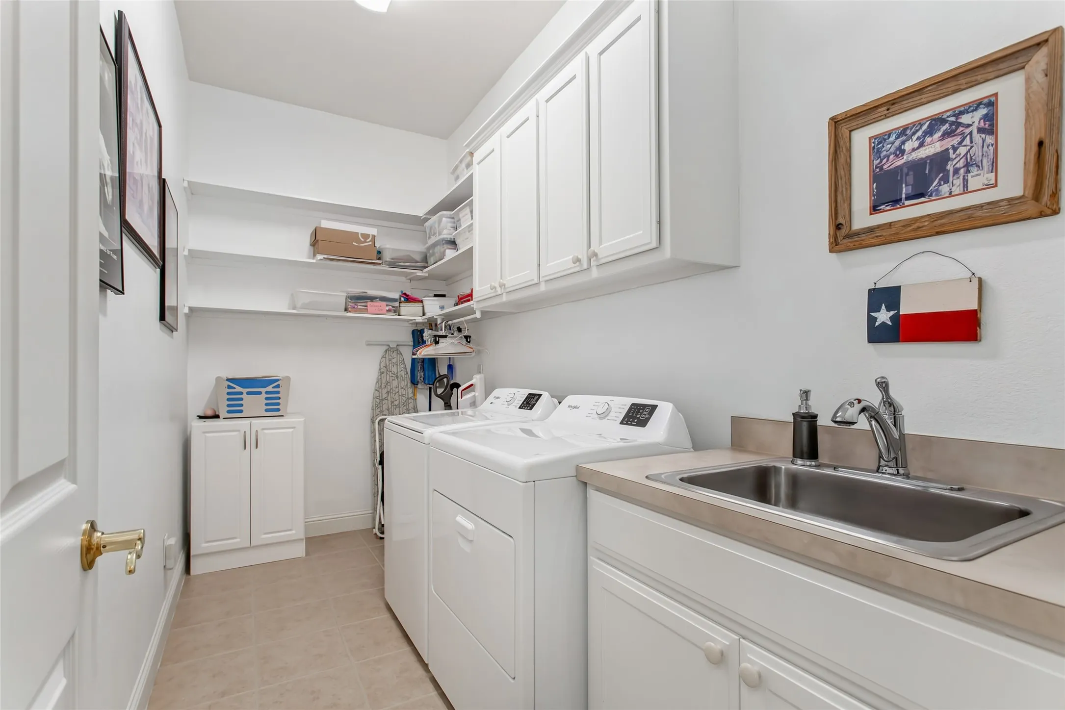 Functional laundry area featuring upper and lower cabinetry, a stainless steel utility sink, and ample counter space