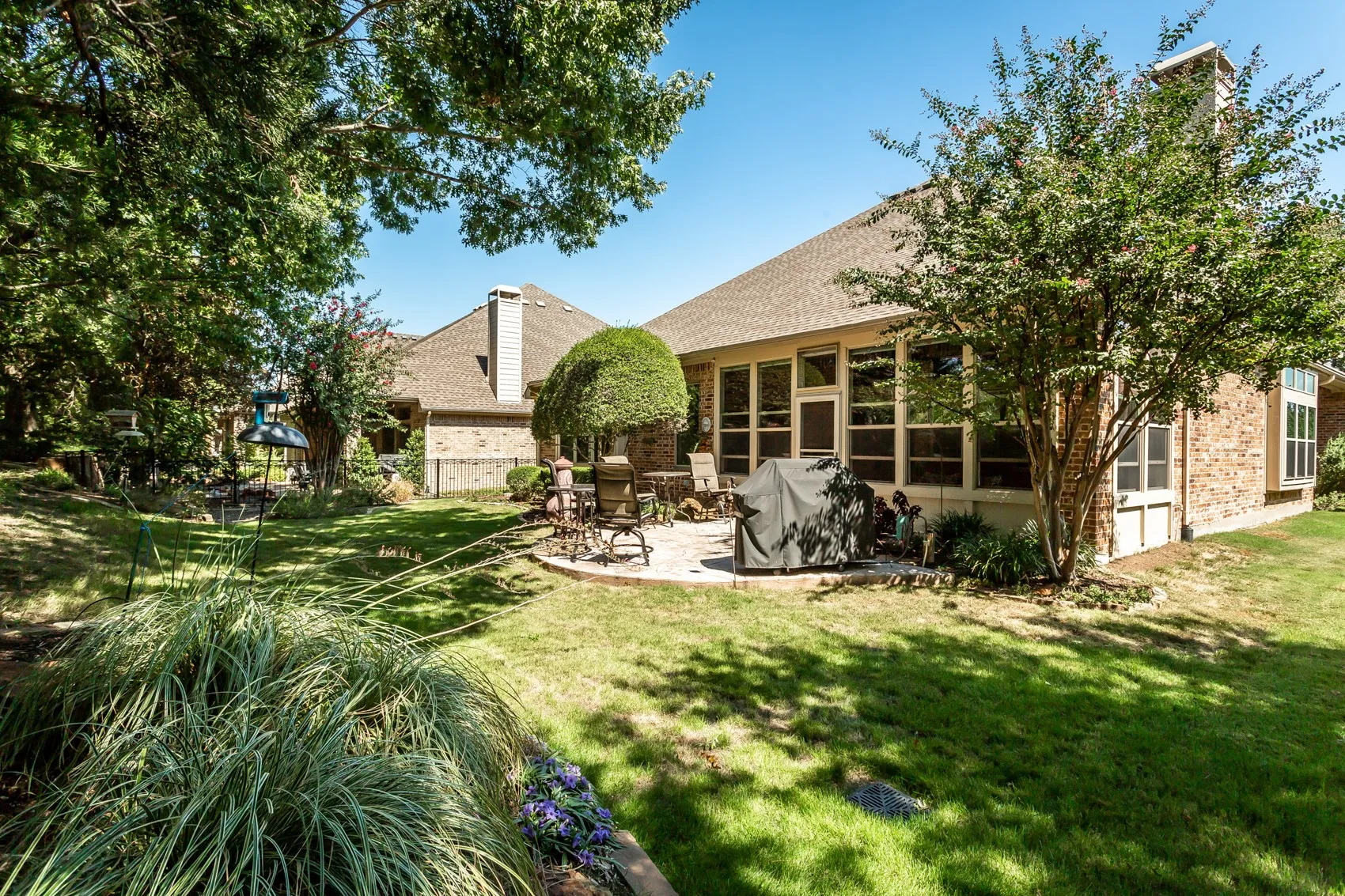 Expansive backyard featuring a manicured lawn, a large patio, and mature trees