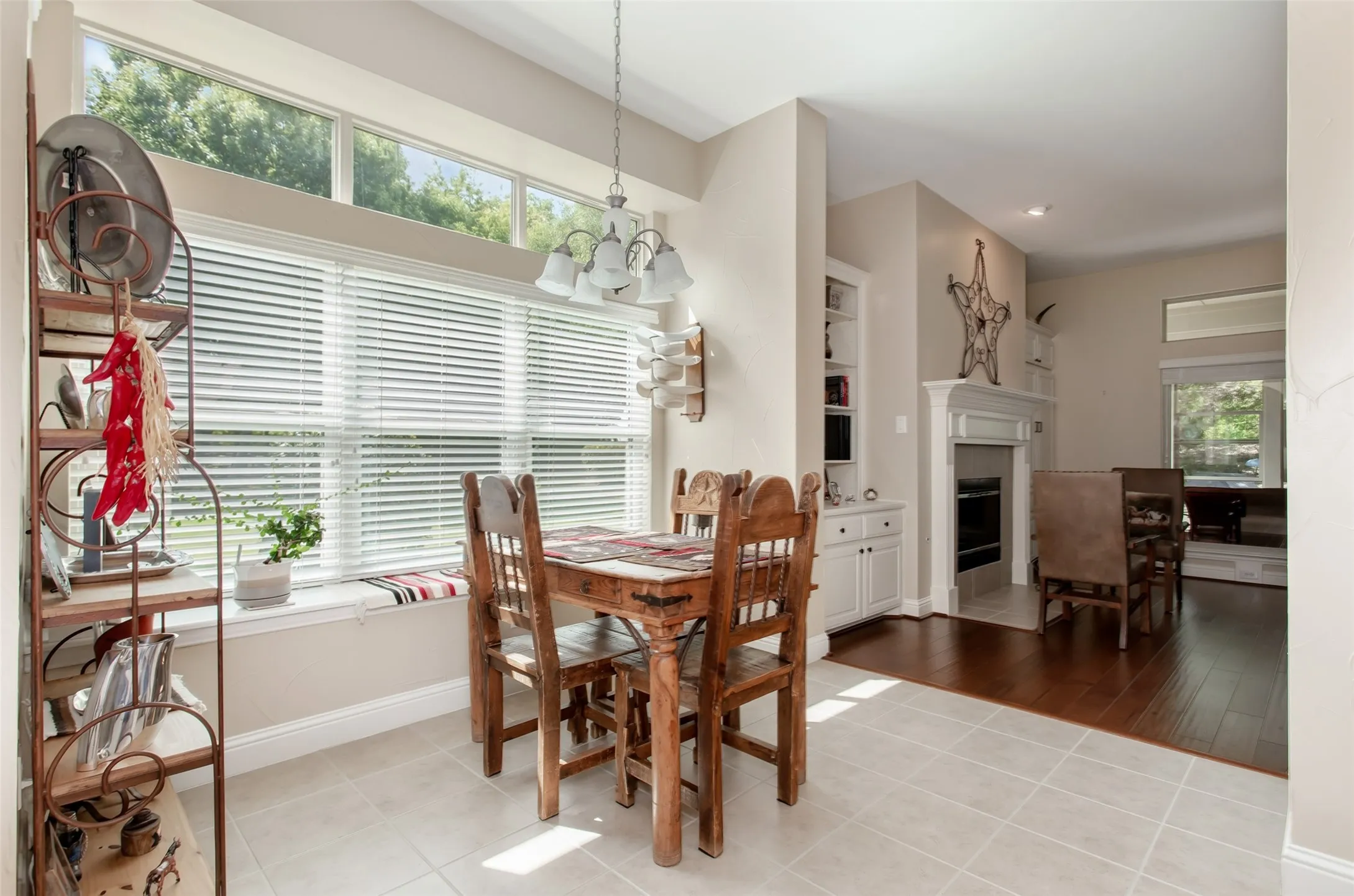 Tile flooring, wood-finish flooring, white built-in cabinetry, white fireplace surround, and transom windows