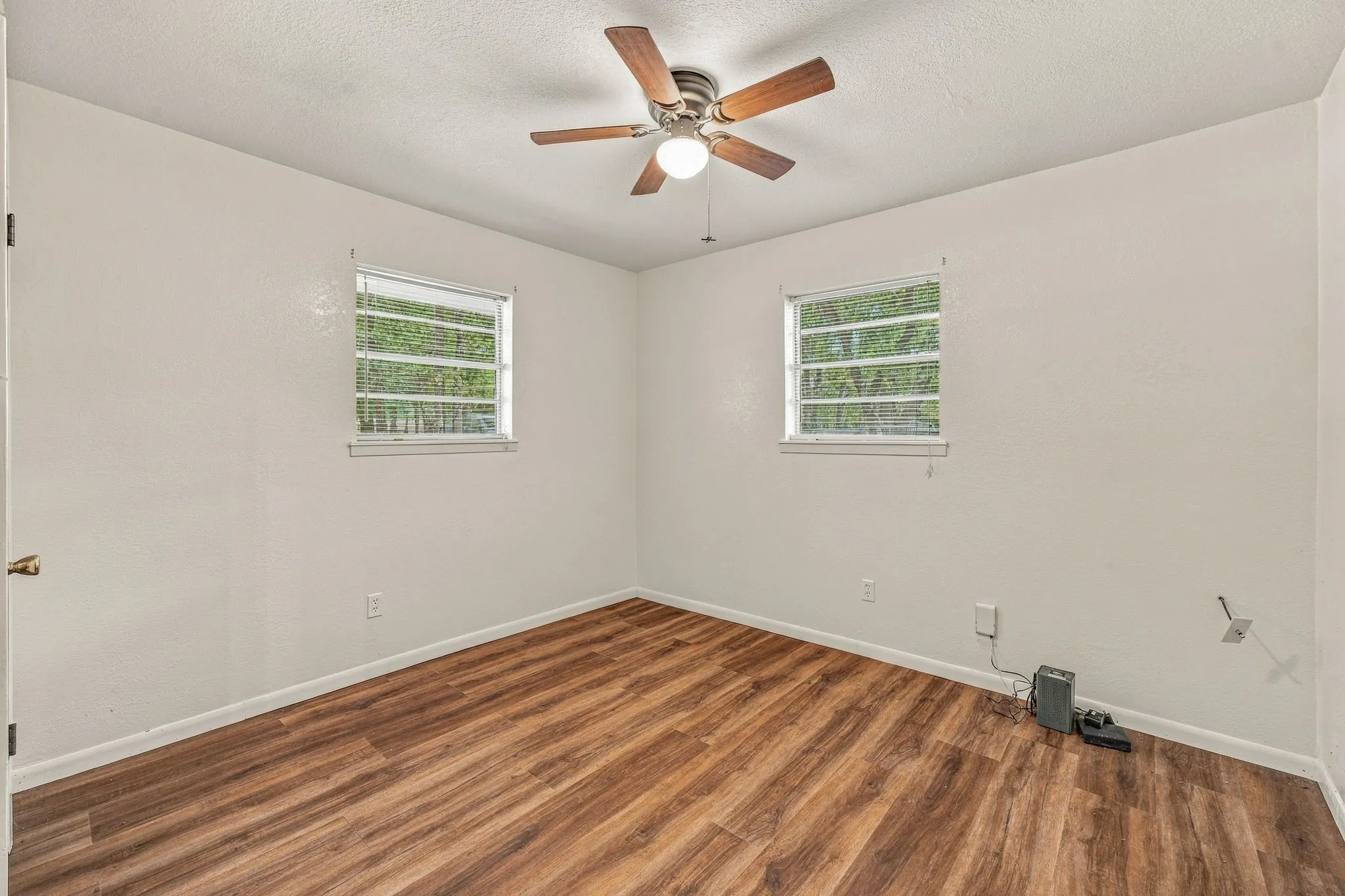 Wood-finish flooring, white walls, and a ceiling fan with integrated lighting