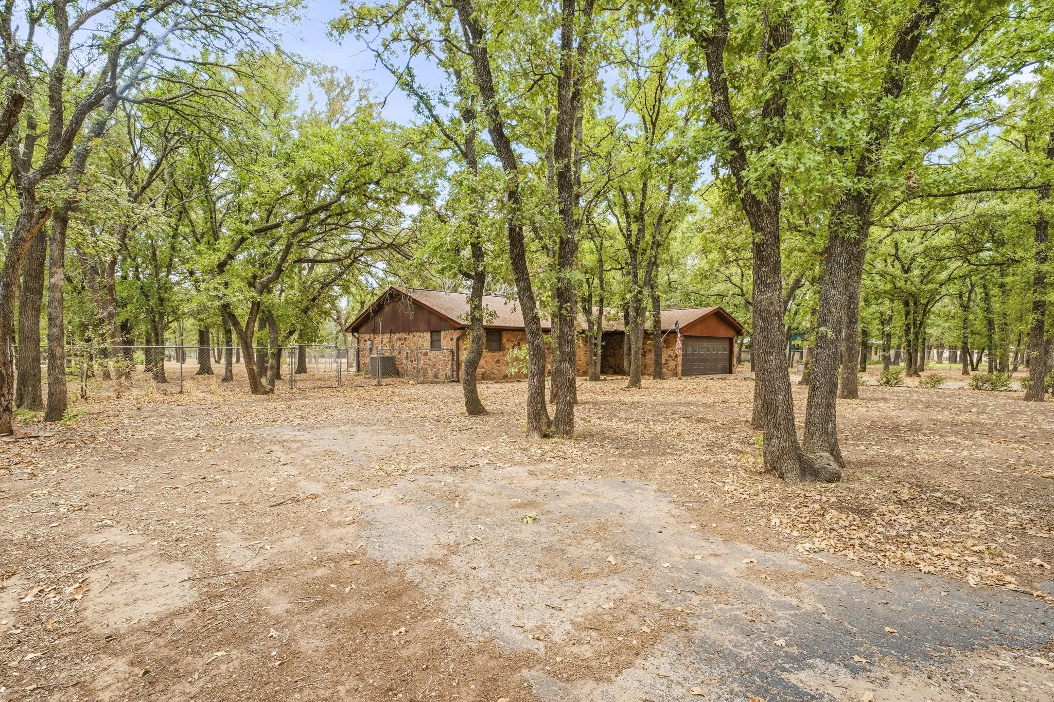 Stone exterior, wood siding, brown shingle roof, attached two-car garage, mature trees