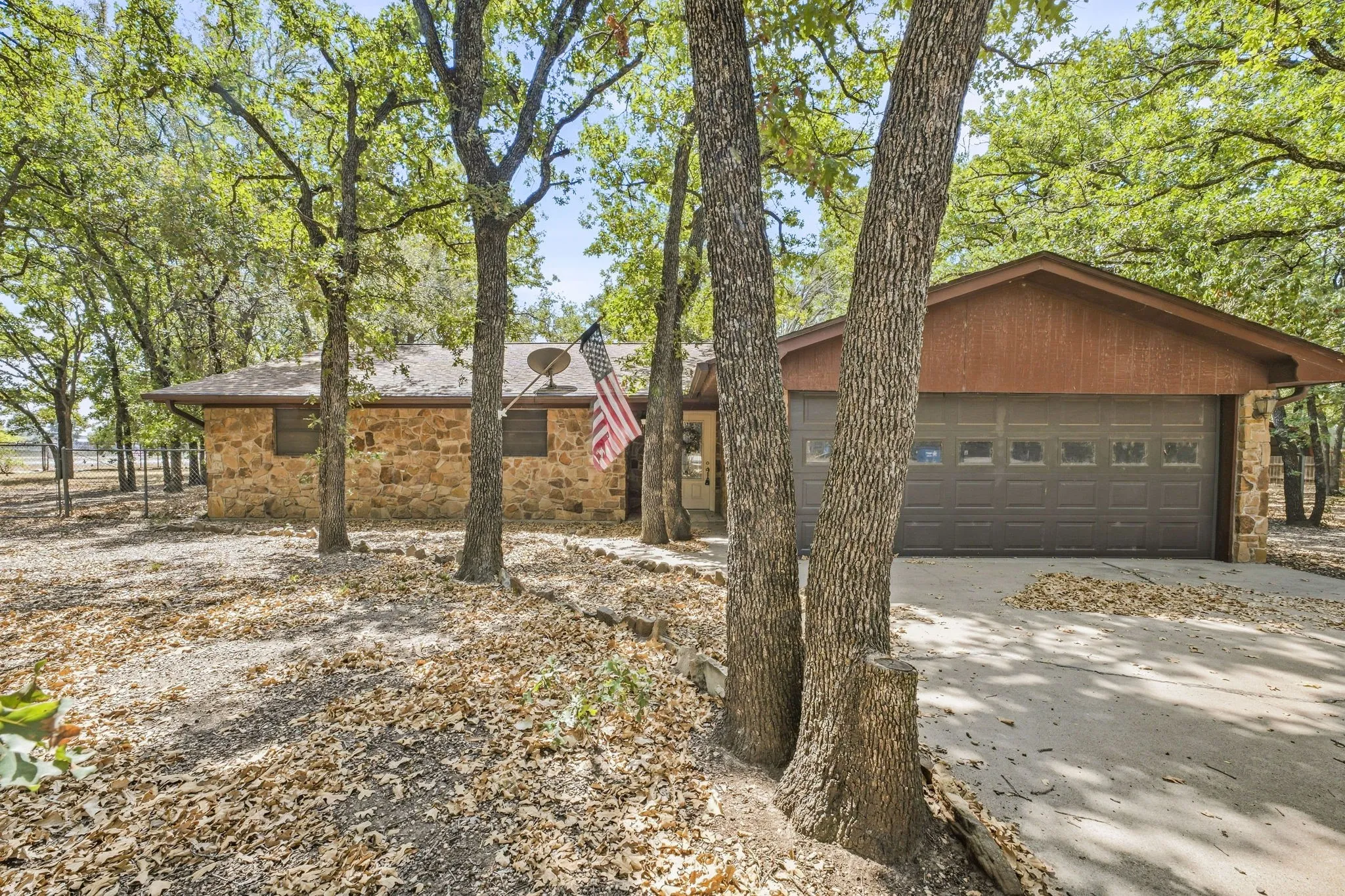 Stone facade residence with an attached garage and a concrete driveway