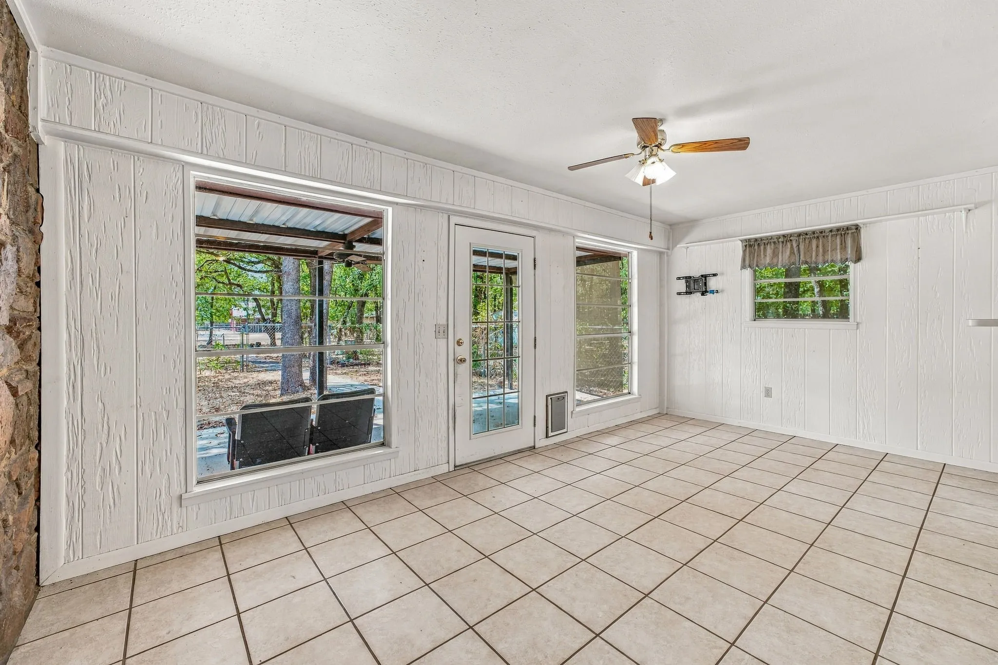 Neutral-toned tile flooring, white plank paneling, and a stone accent wall