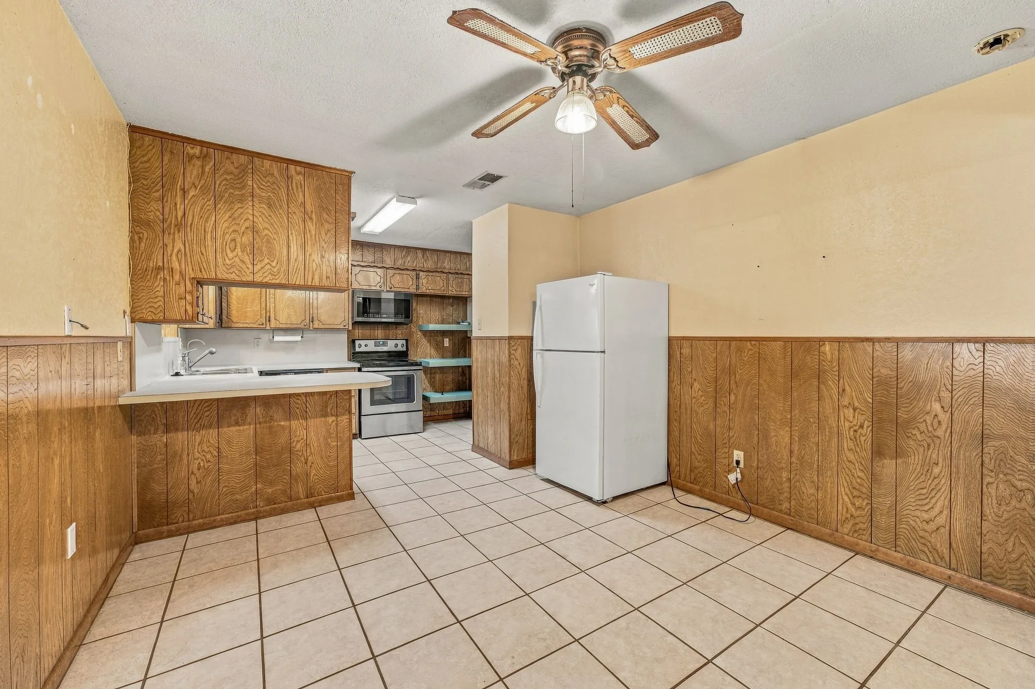 Kitchen area featuring wood-paneled walls, tile flooring, and wood cabinetry