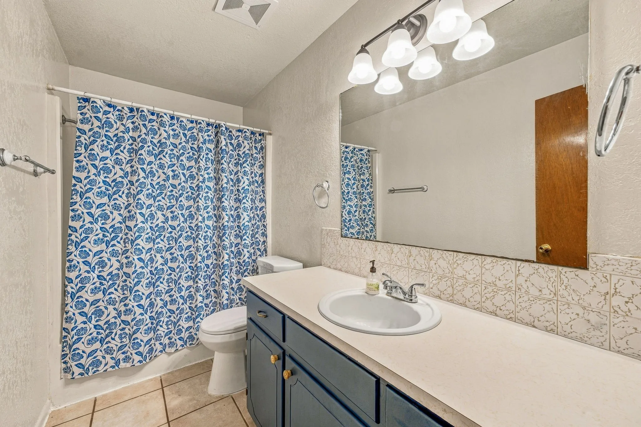 Bathroom featuring a vanity with a white countertop, blue cabinetry, a rectangular mirror, and an overhead light fixture