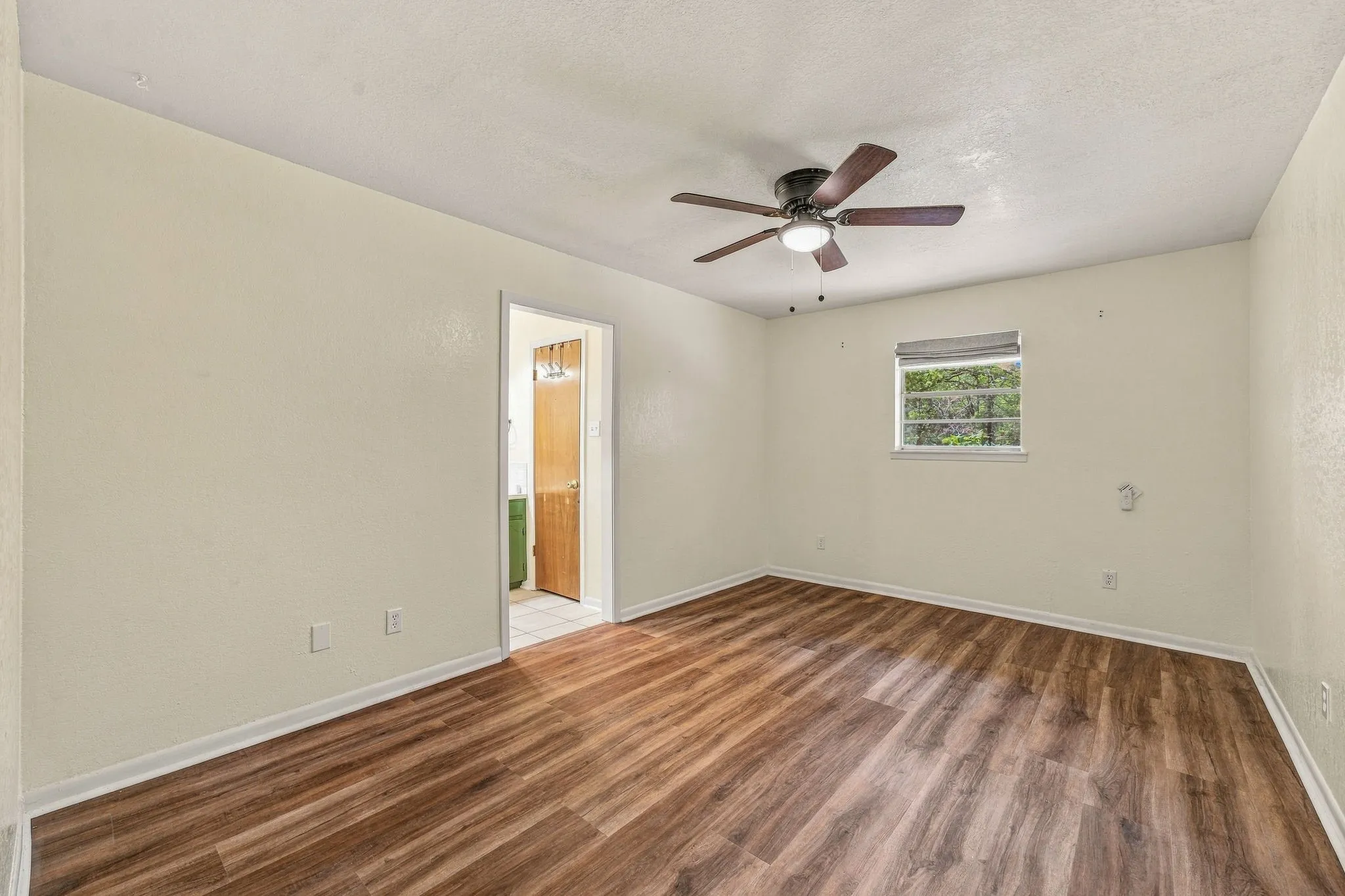 Wood-finish flooring, ceiling fan with integrated lighting, and a single window with blinds