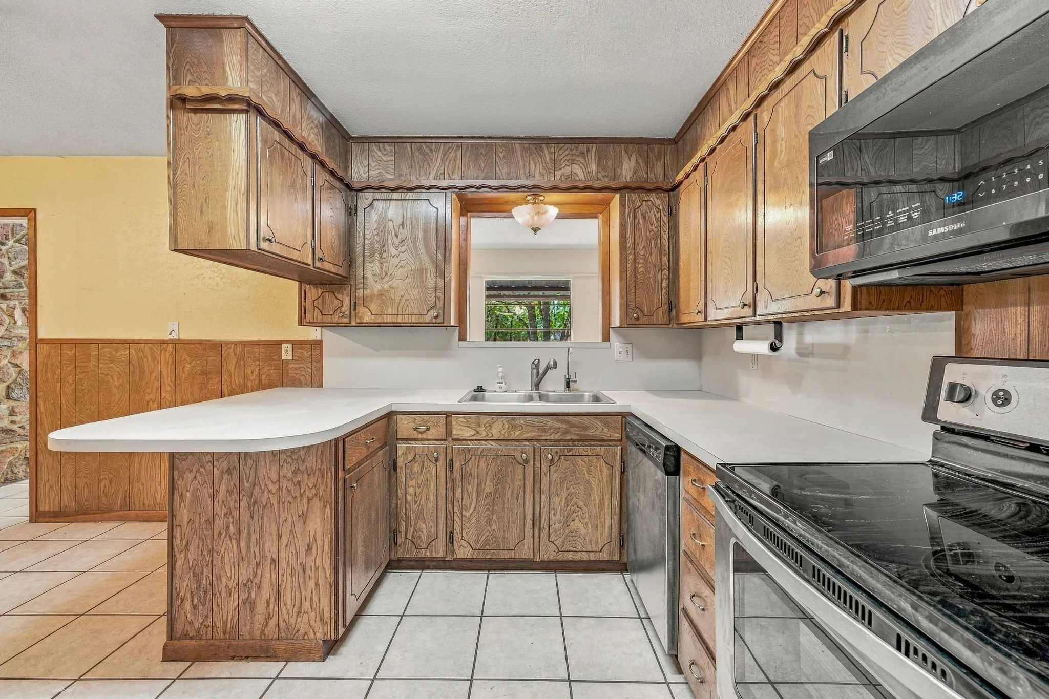 Kitchen featuring wood-finish cabinetry, white countertops, a double basin sink, and tile flooring