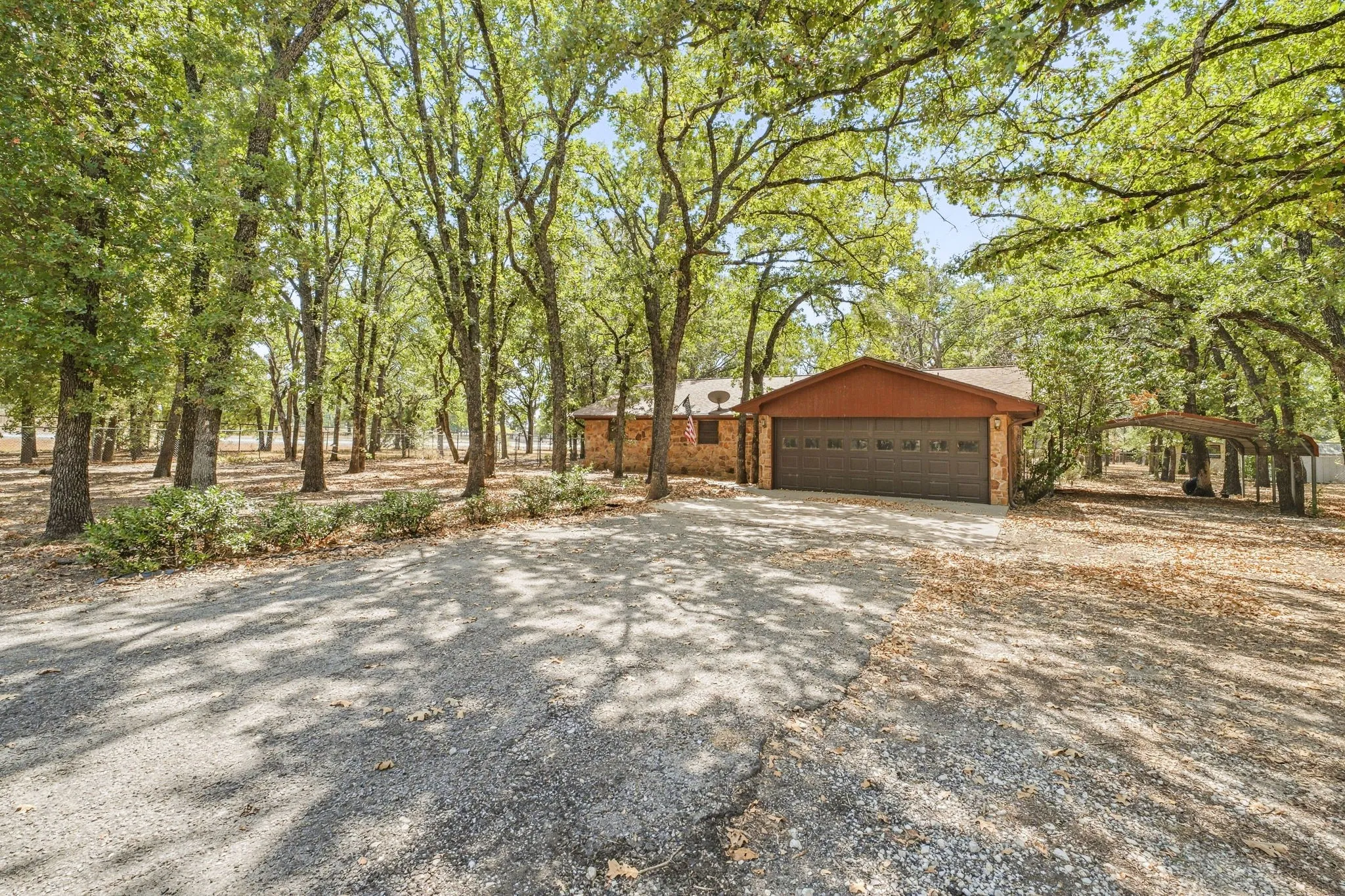 Brick exterior with an attached two-car garage, surrounded by mature trees