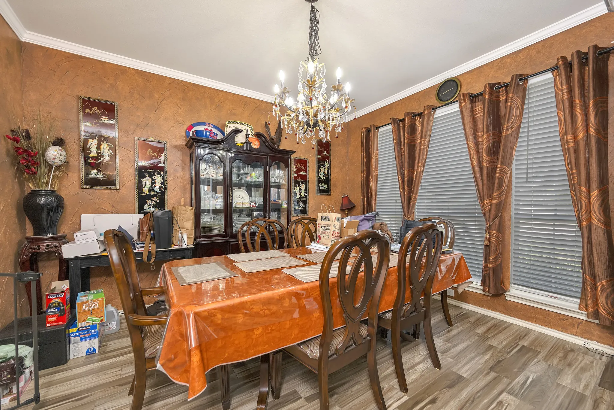 Wood-finish flooring with a textured wall finish, crown molding, and multiple windows