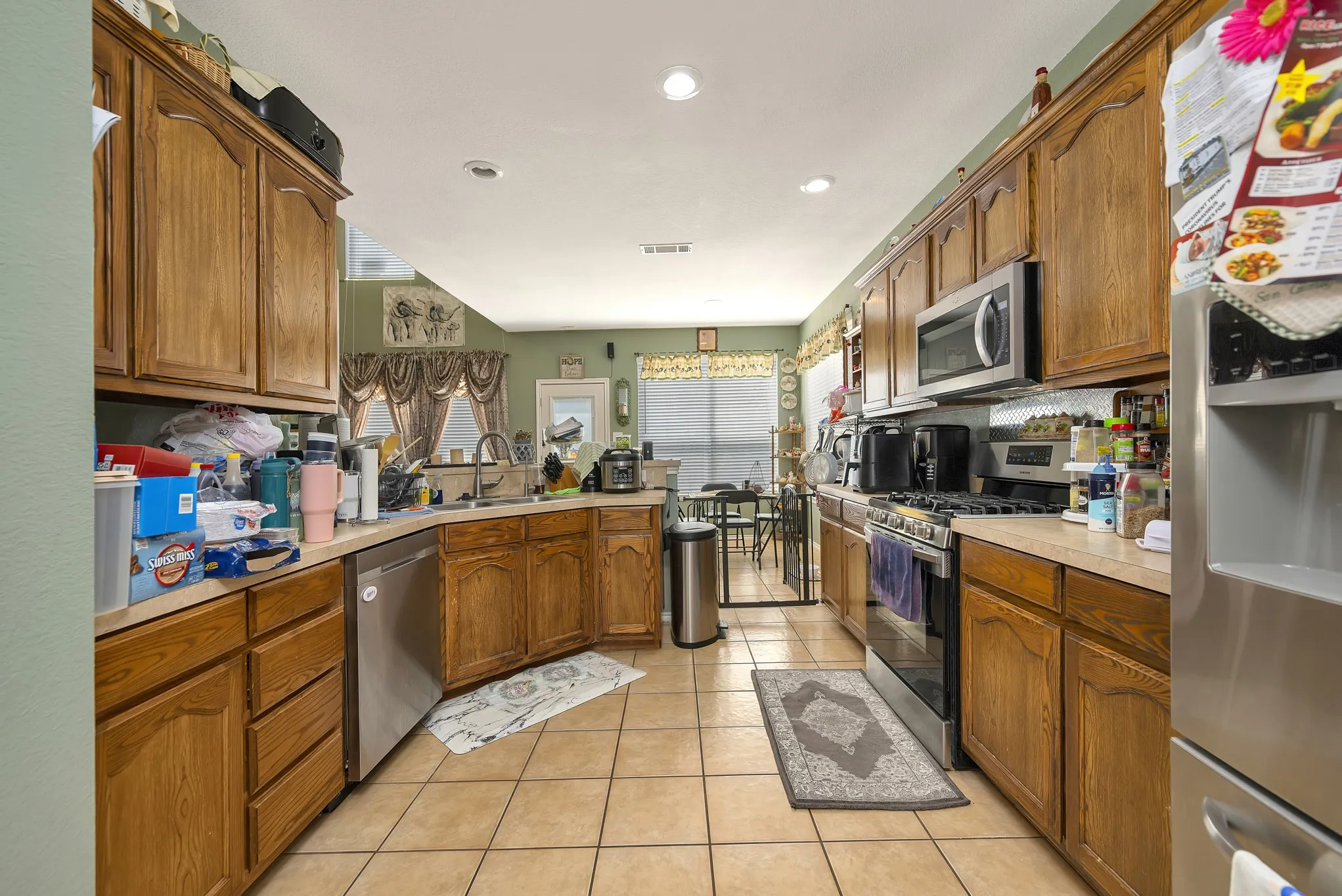 Kitchen featuring wood cabinetry, stainless steel appliances, recessed lighting, and tile flooring