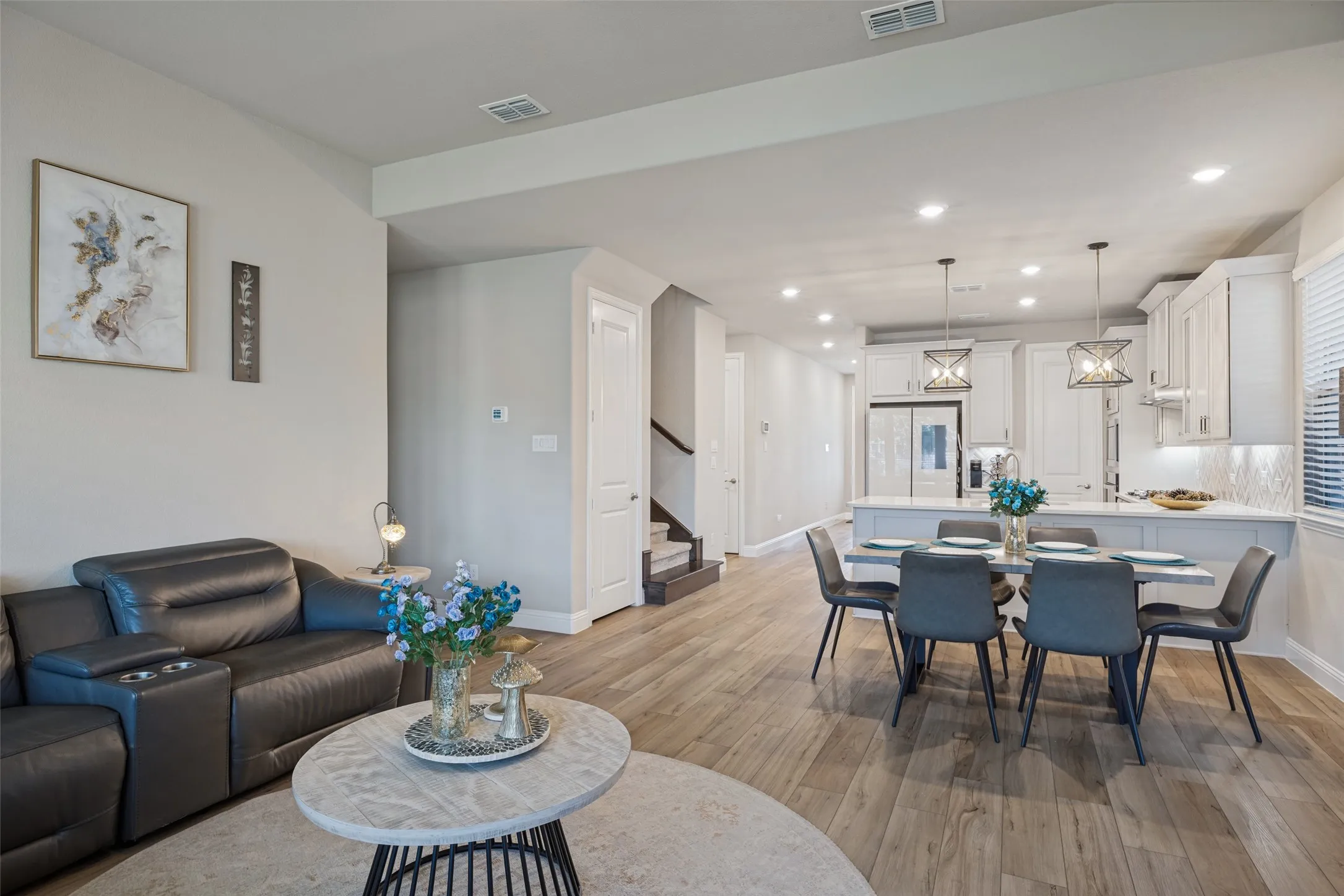 Open-concept living area featuring wood-finish flooring, recessed lighting, and a kitchen island with pendant lights