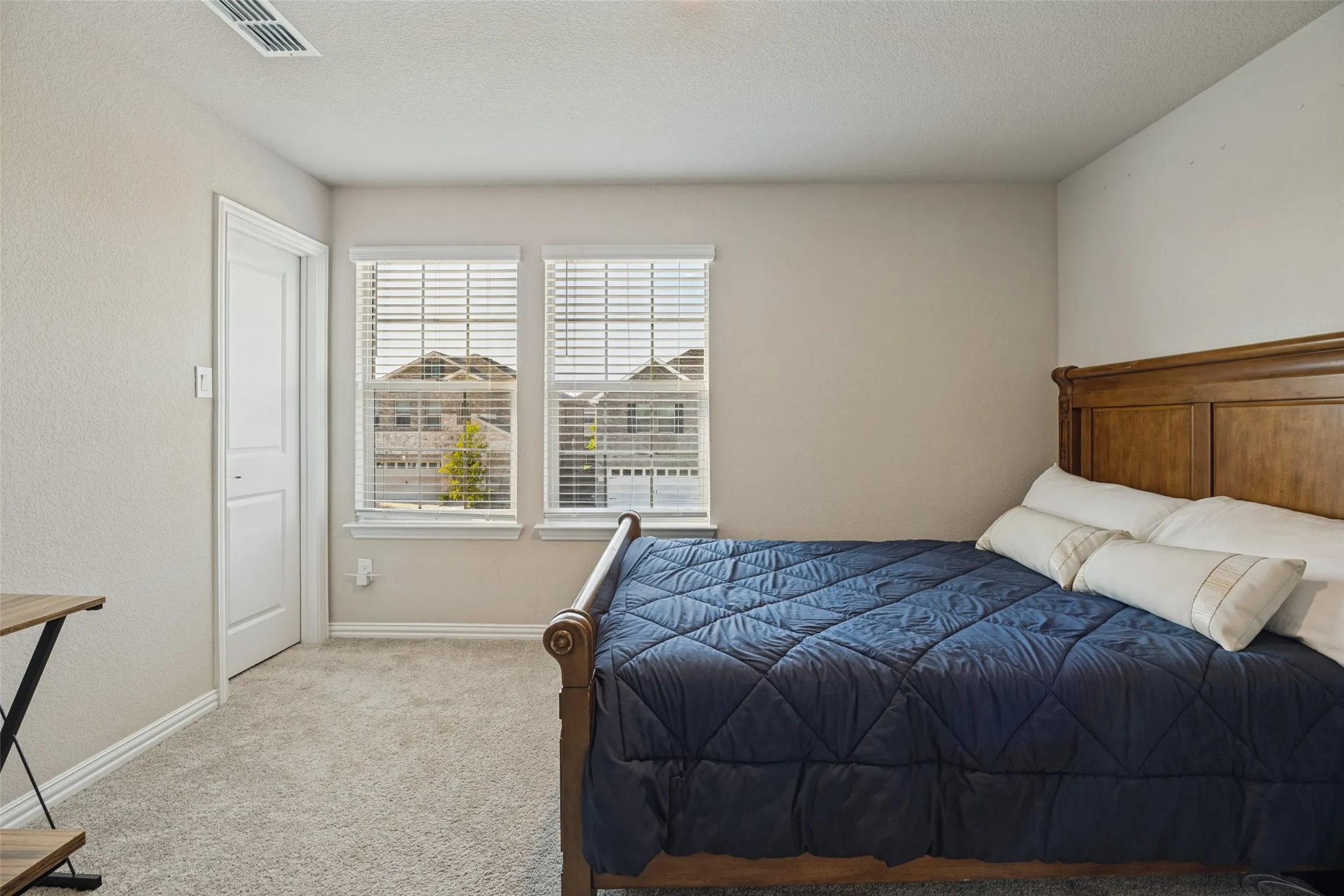 Carpeted flooring throughout, neutral wall paint, and two windows with blinds