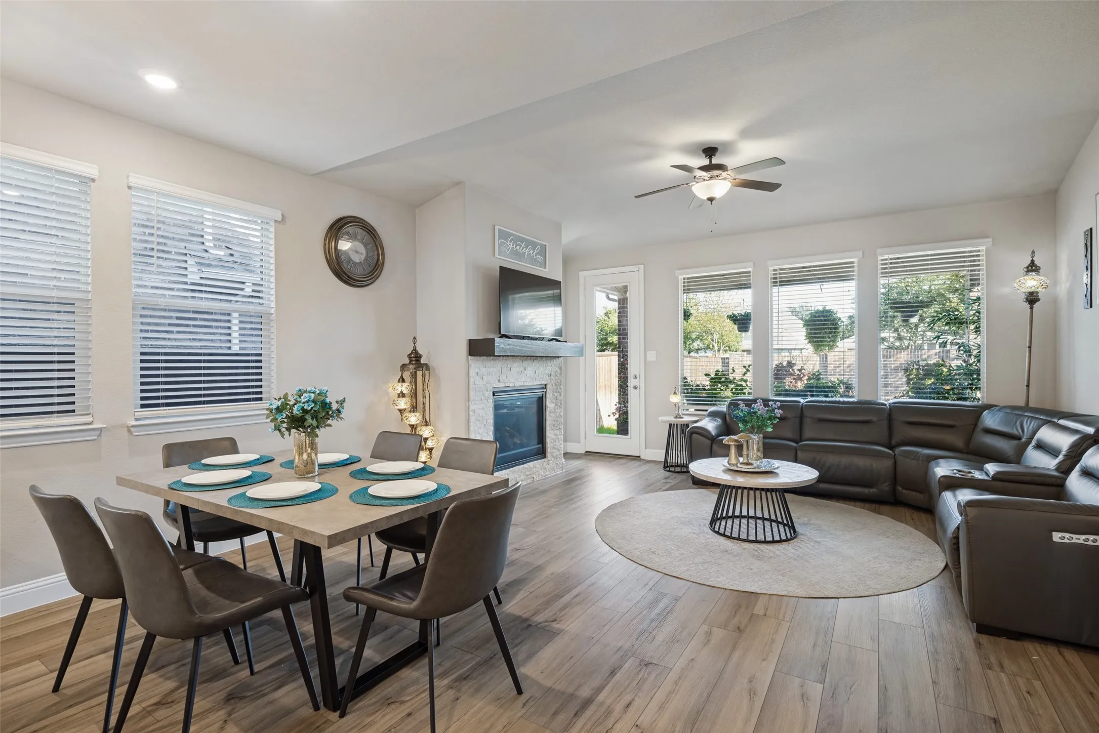 Recessed lighting, wood-finish flooring, ceiling fan, fireplace with tile surround, multiple windows with blinds
