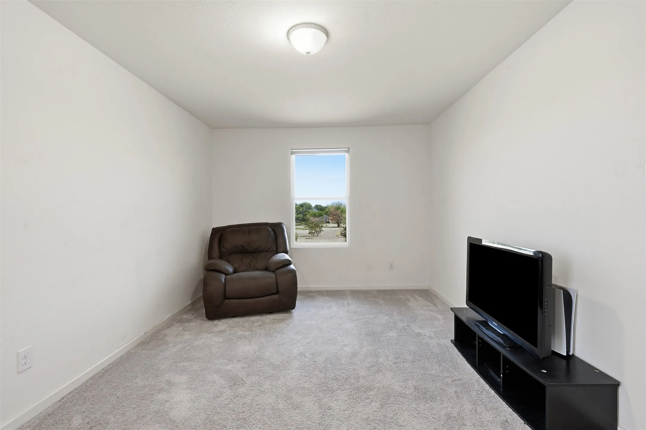 Carpeted room with a single window, white walls, and an overhead light fixture