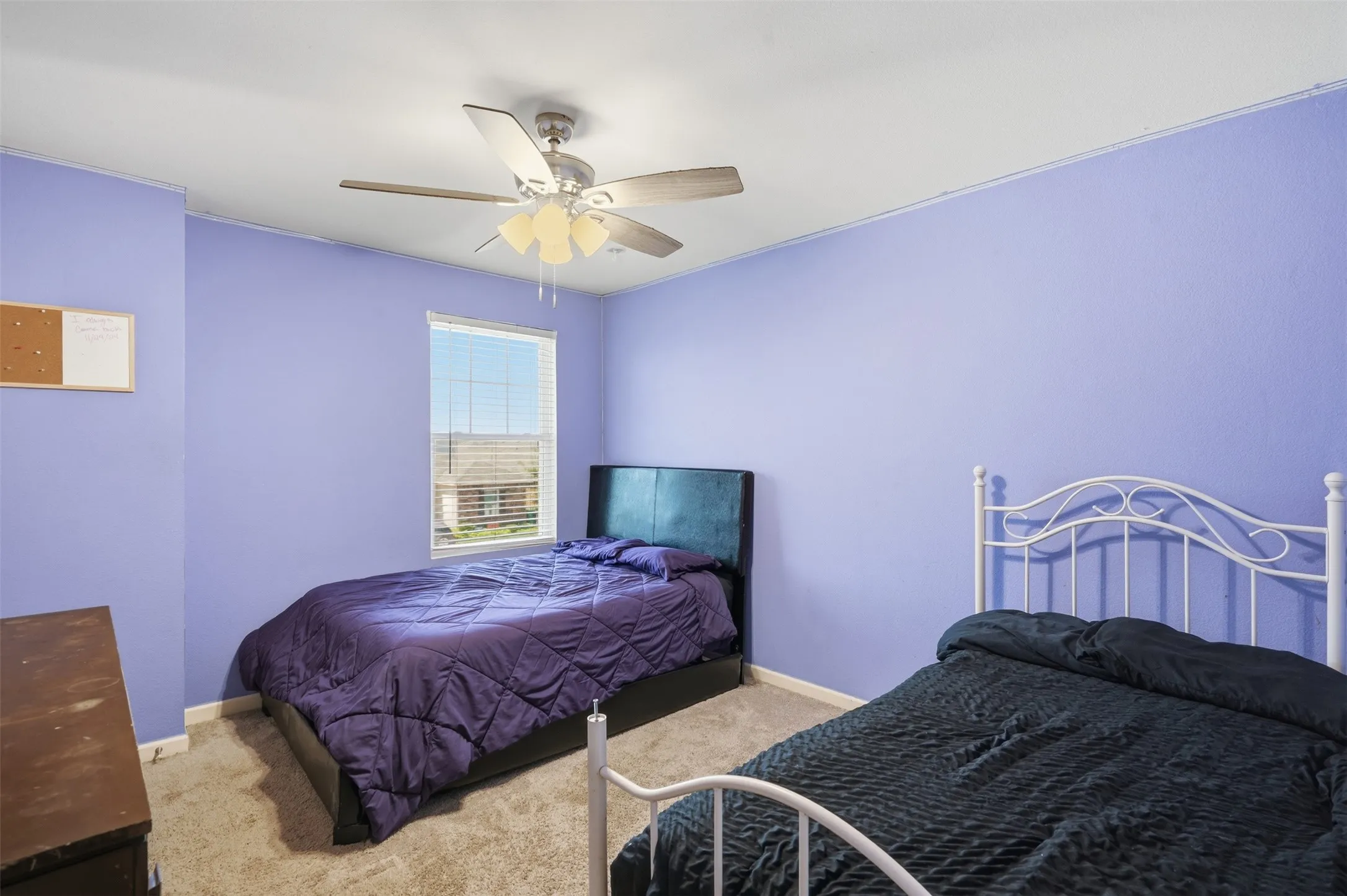Room with textured lavender walls, carpeted flooring, and a ceiling fan with integrated lighting