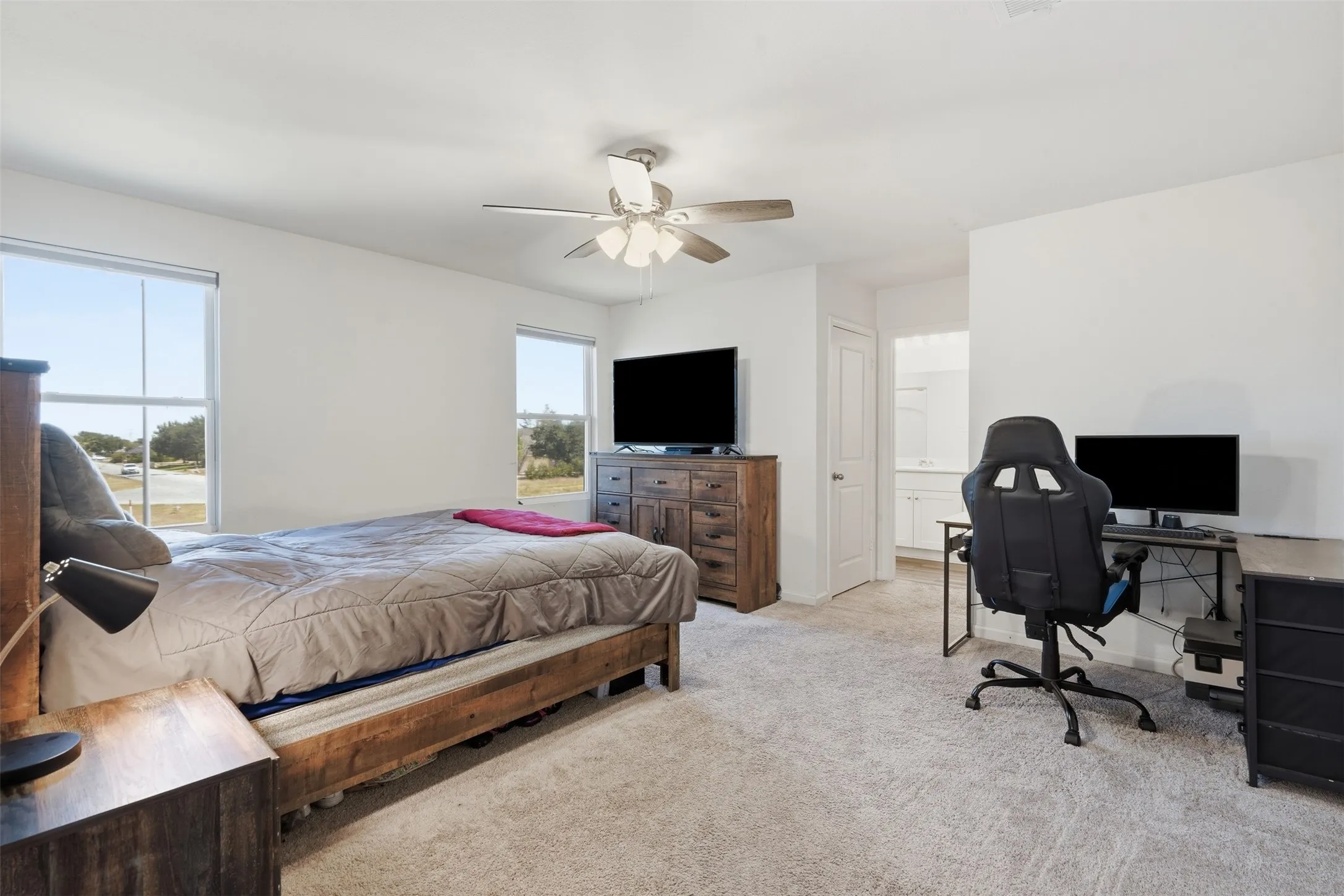 Carpeted bedroom with two windows, a ceiling fan, and a light-colored wood-finish dresser