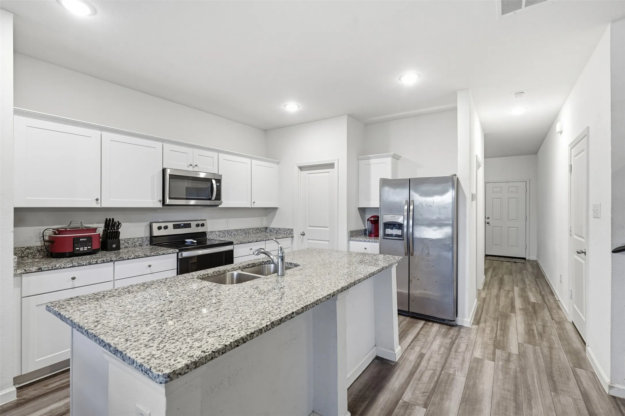 Kitchen featuring a center island, light-toned countertops, white cabinetry, and stainless steel appliances