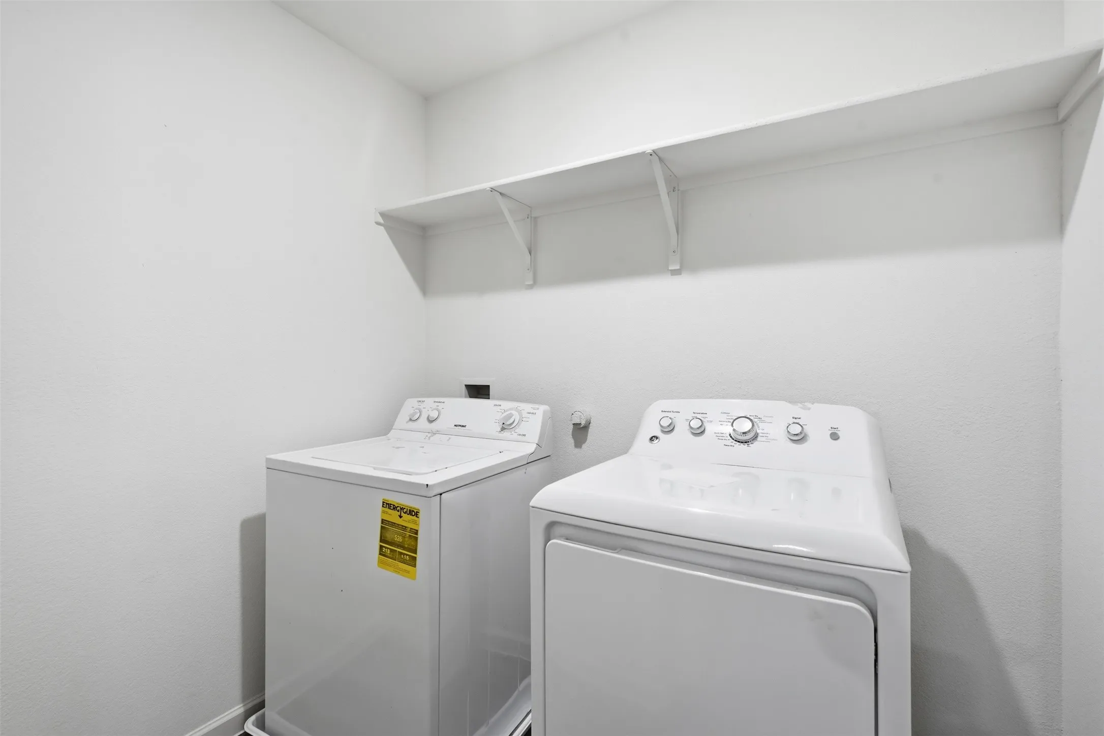 Utility area with a built-in shelf and white walls