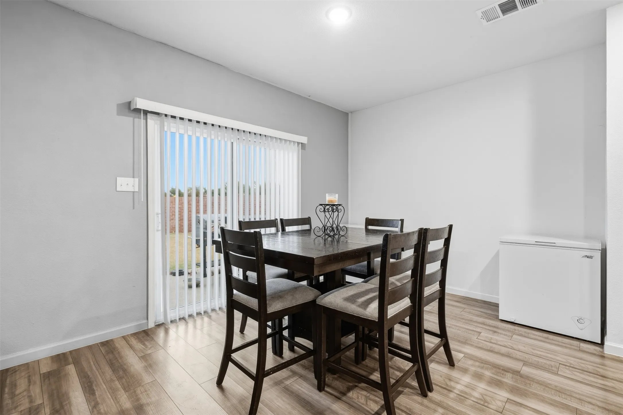 Wood-finish flooring, white walls, and a sliding glass door with vertical blinds