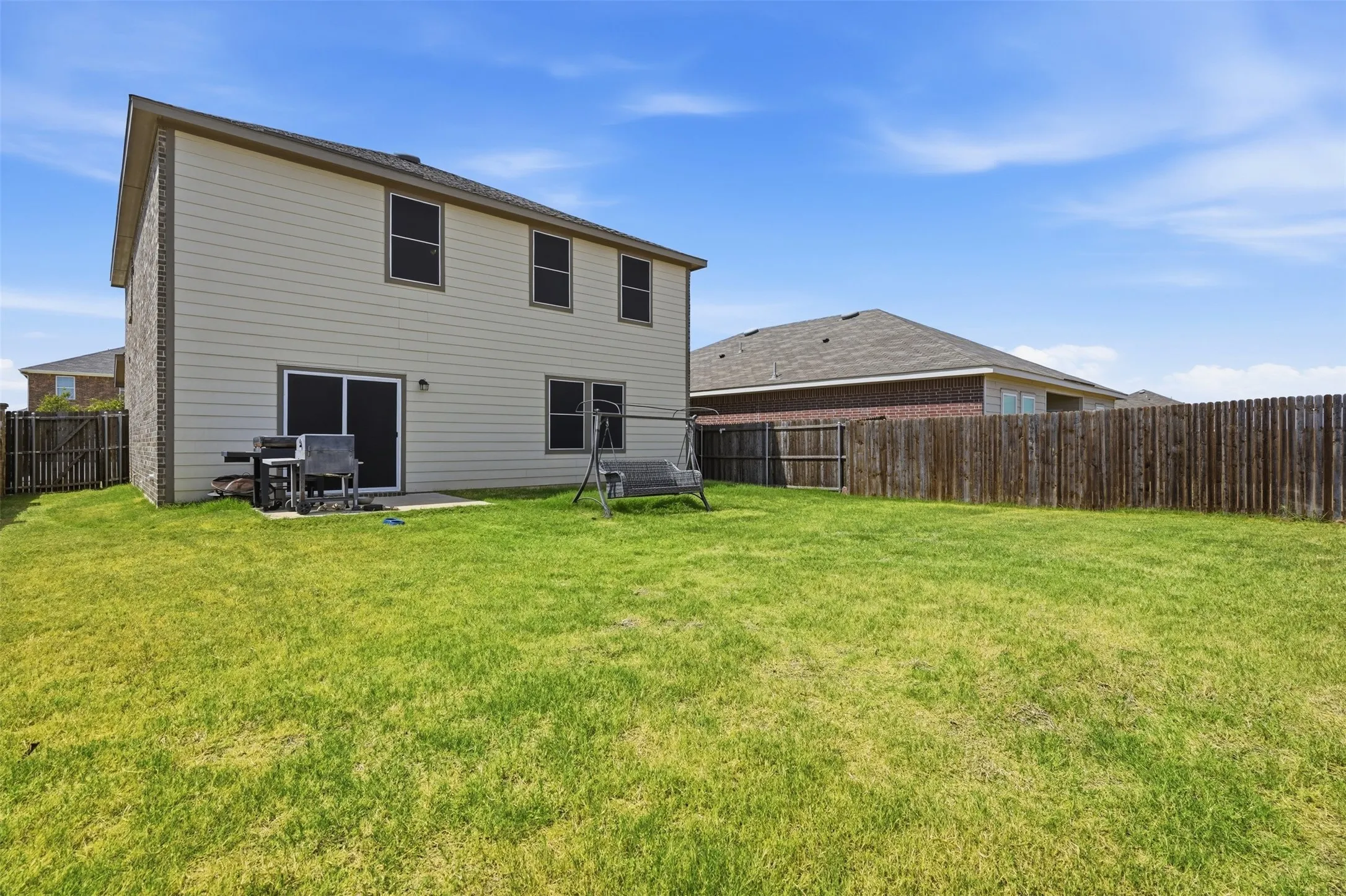 Spacious backyard featuring a wood privacy fence and a concrete patio with sliding glass doors