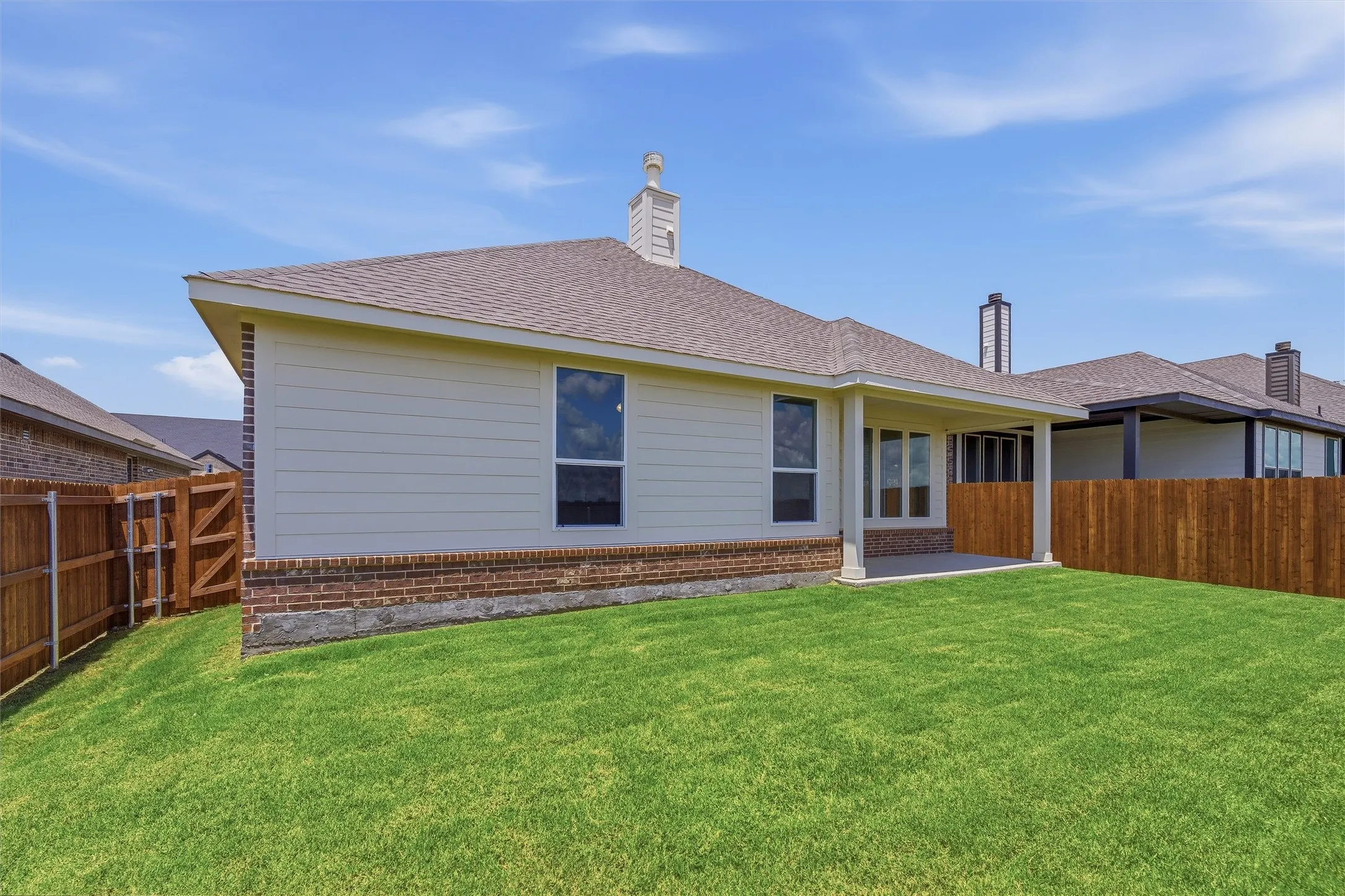 Spacious backyard featuring a manicured lawn, full privacy fencing, and a covered concrete patio