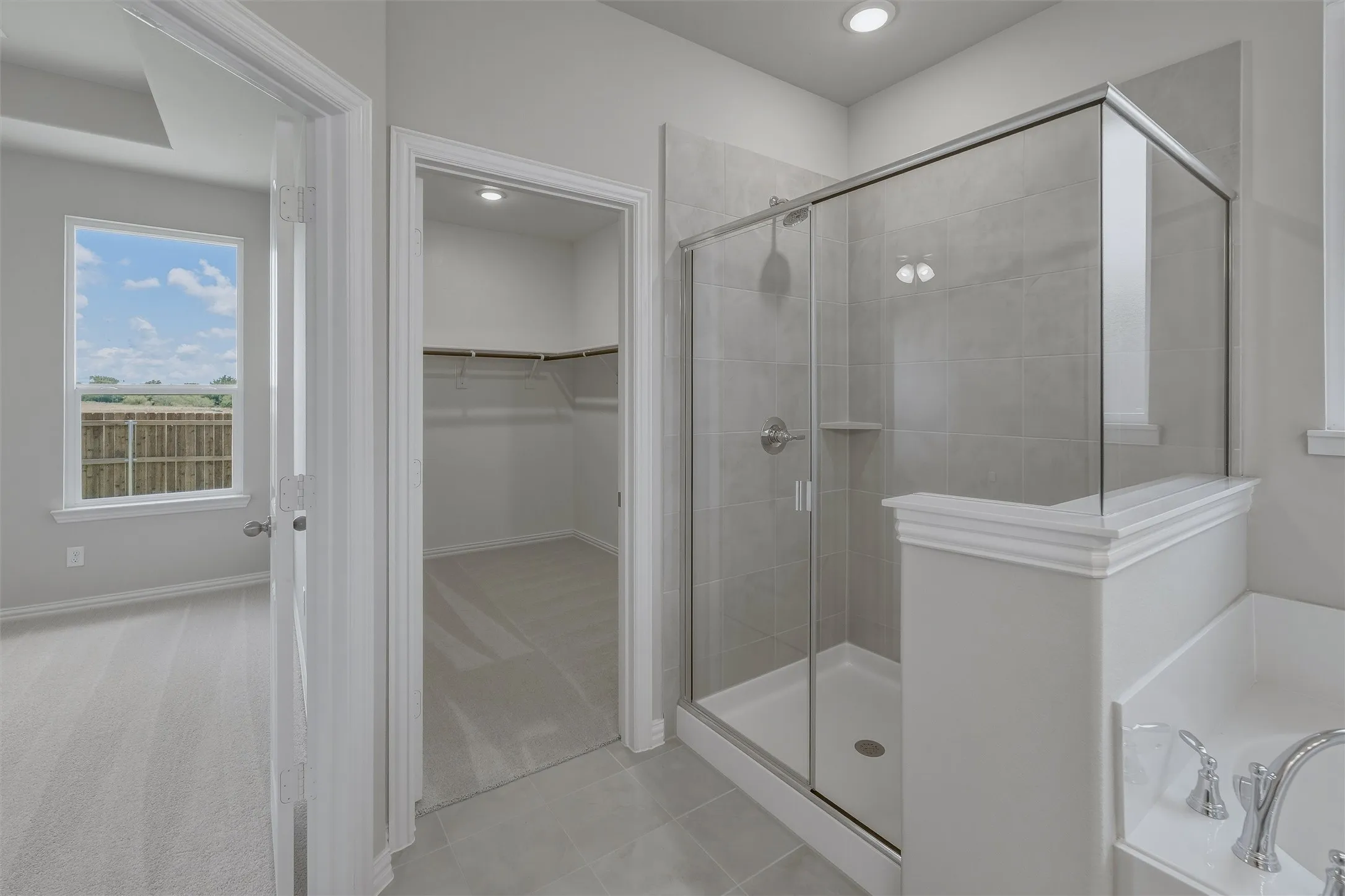 Bathroom featuring a glass-enclosed shower with tile surround, a built-in bathtub with chrome fixtures, and light gray floor tiling