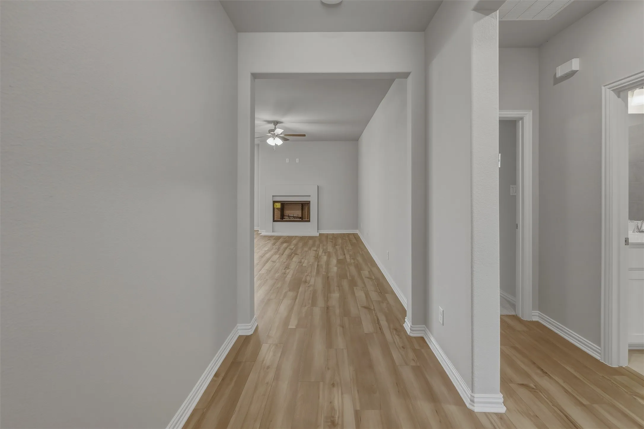 Interior hallway with wood-finish flooring extending into a living space