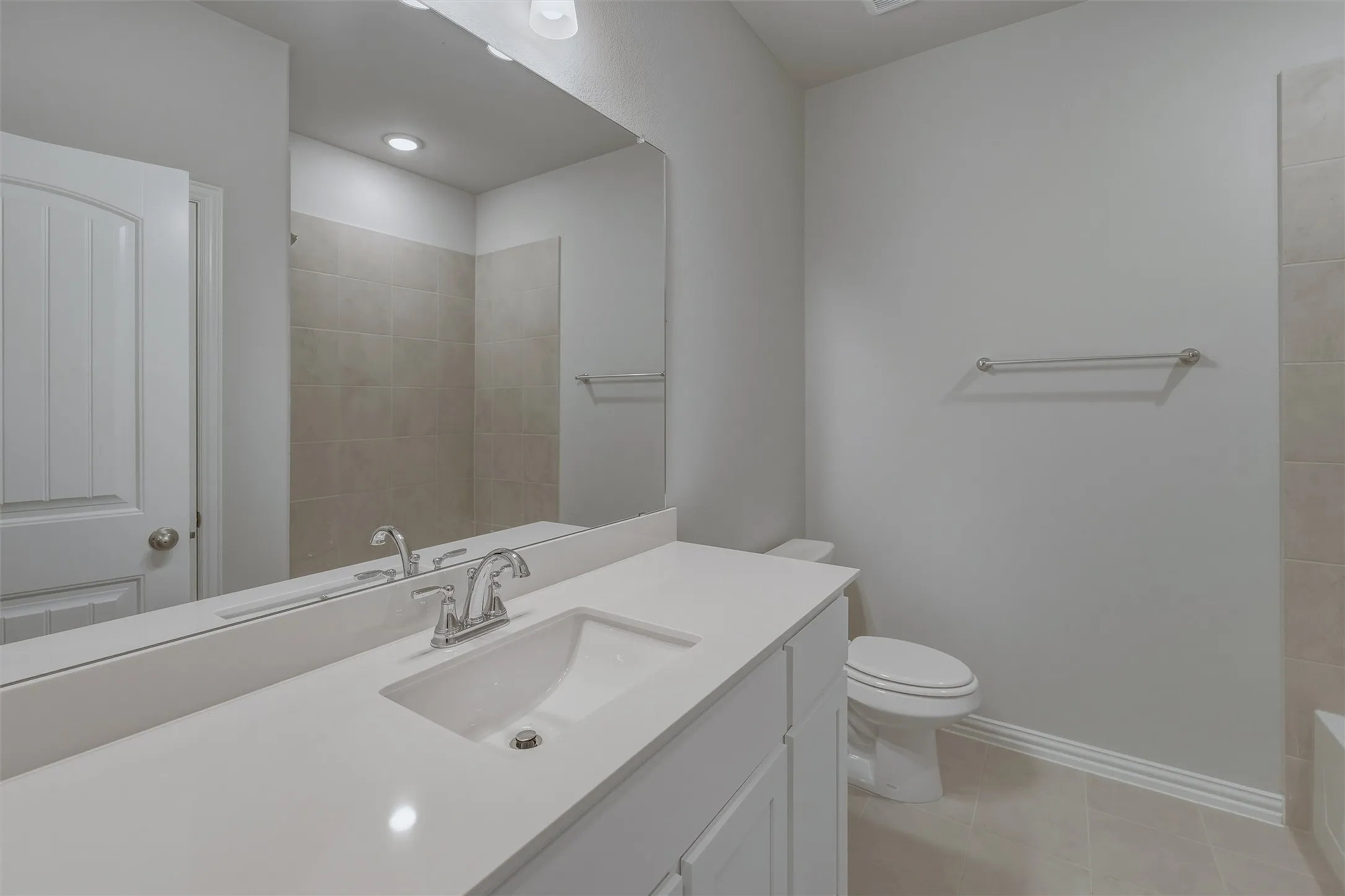 Bathroom vanity featuring a single basin sink set in a light-toned countertop, with a full-width mirror