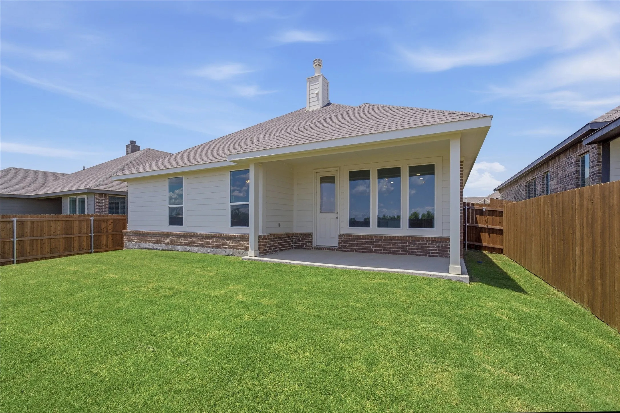 Expansive green lawn surrounds a covered patio
