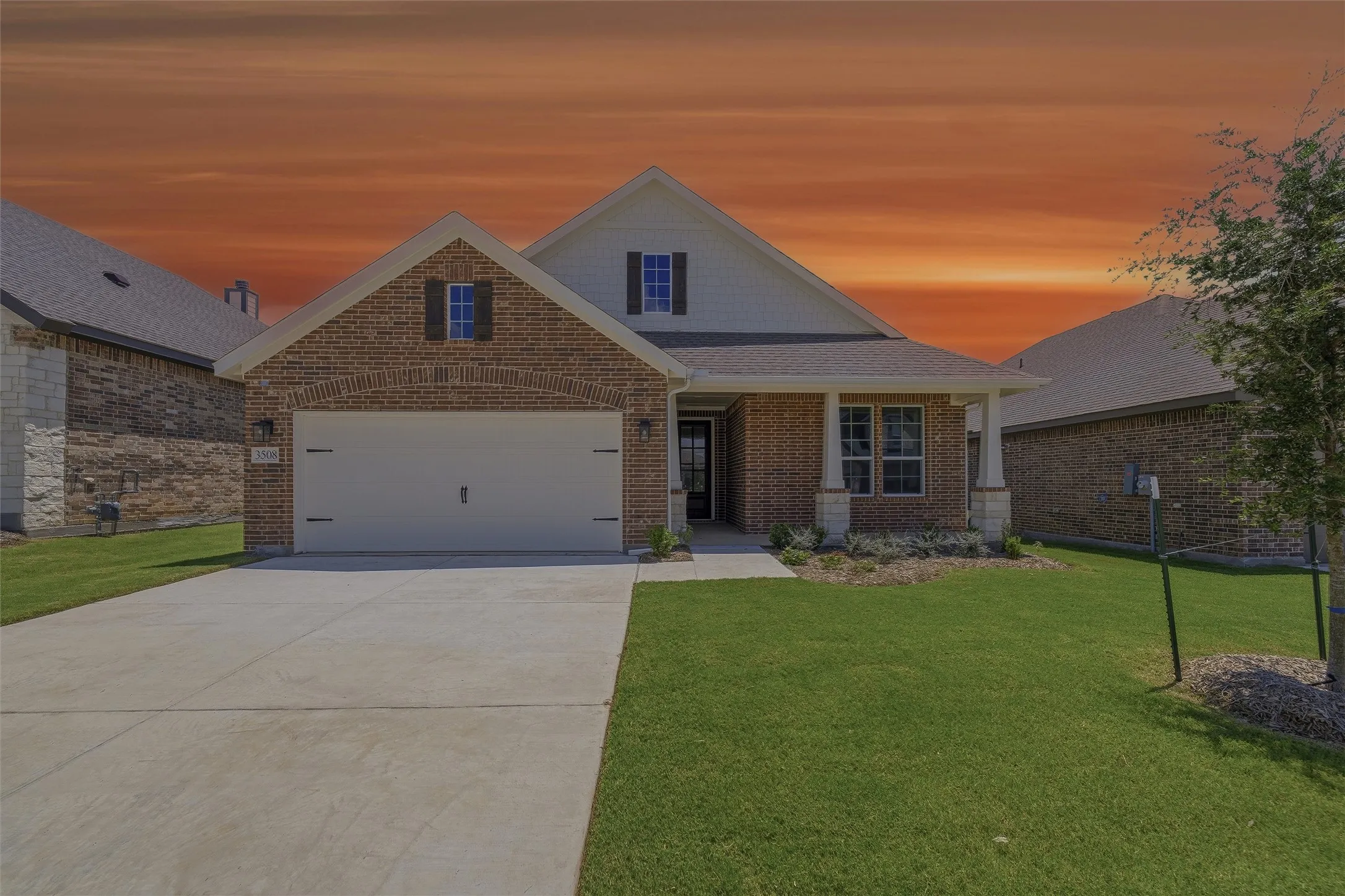 Brick and siding exterior with a two-car garage, covered entry, and a manicured lawn