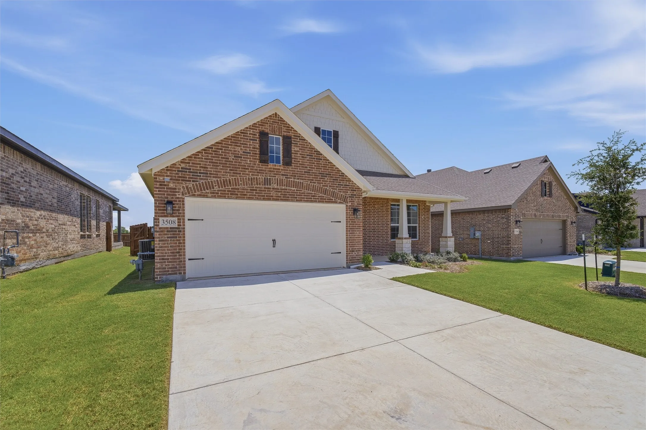 Brick and siding exterior featuring a two-car garage with a concrete driveway