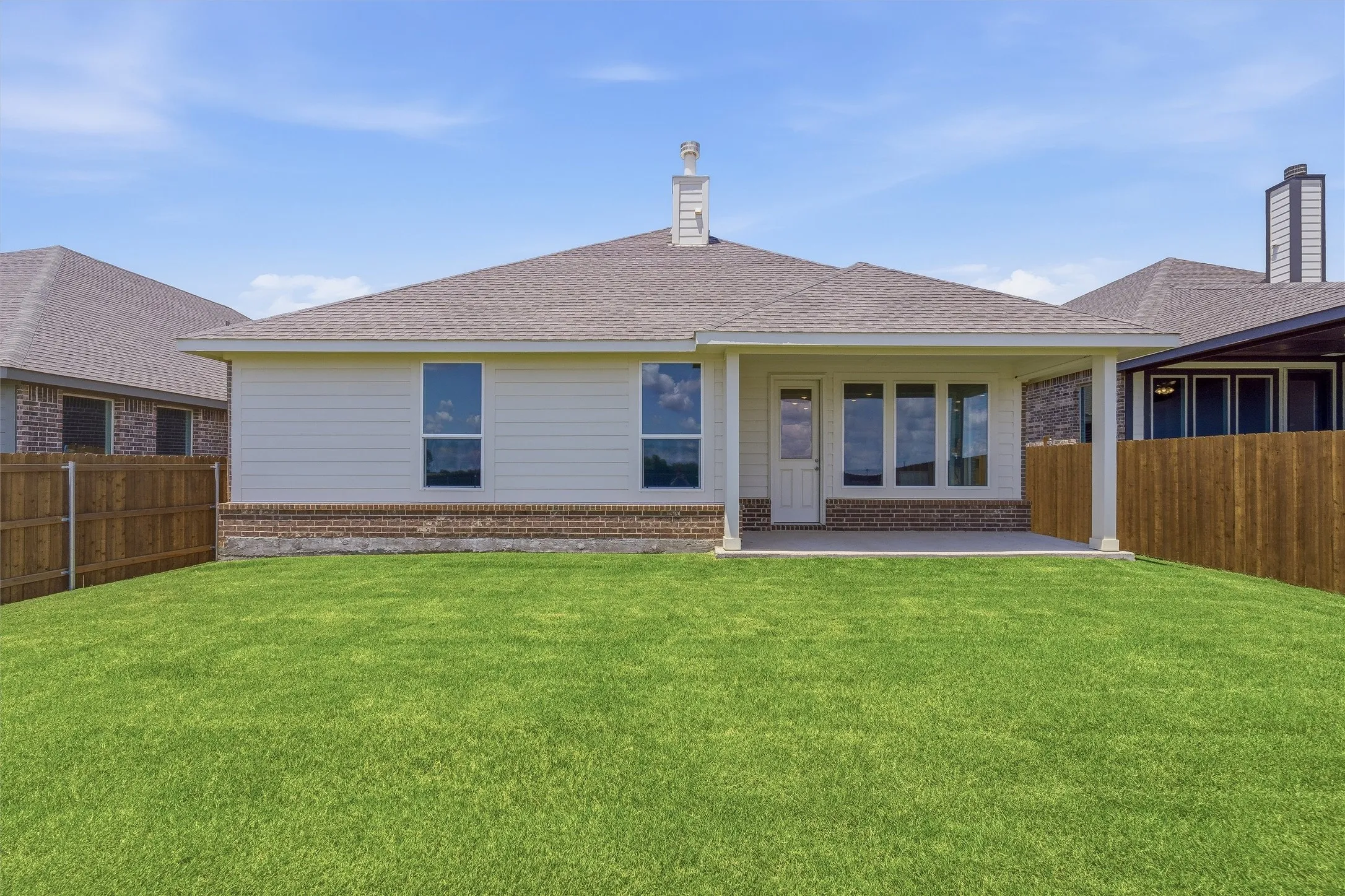 Expansive rear lawn framed by a wooden privacy fence