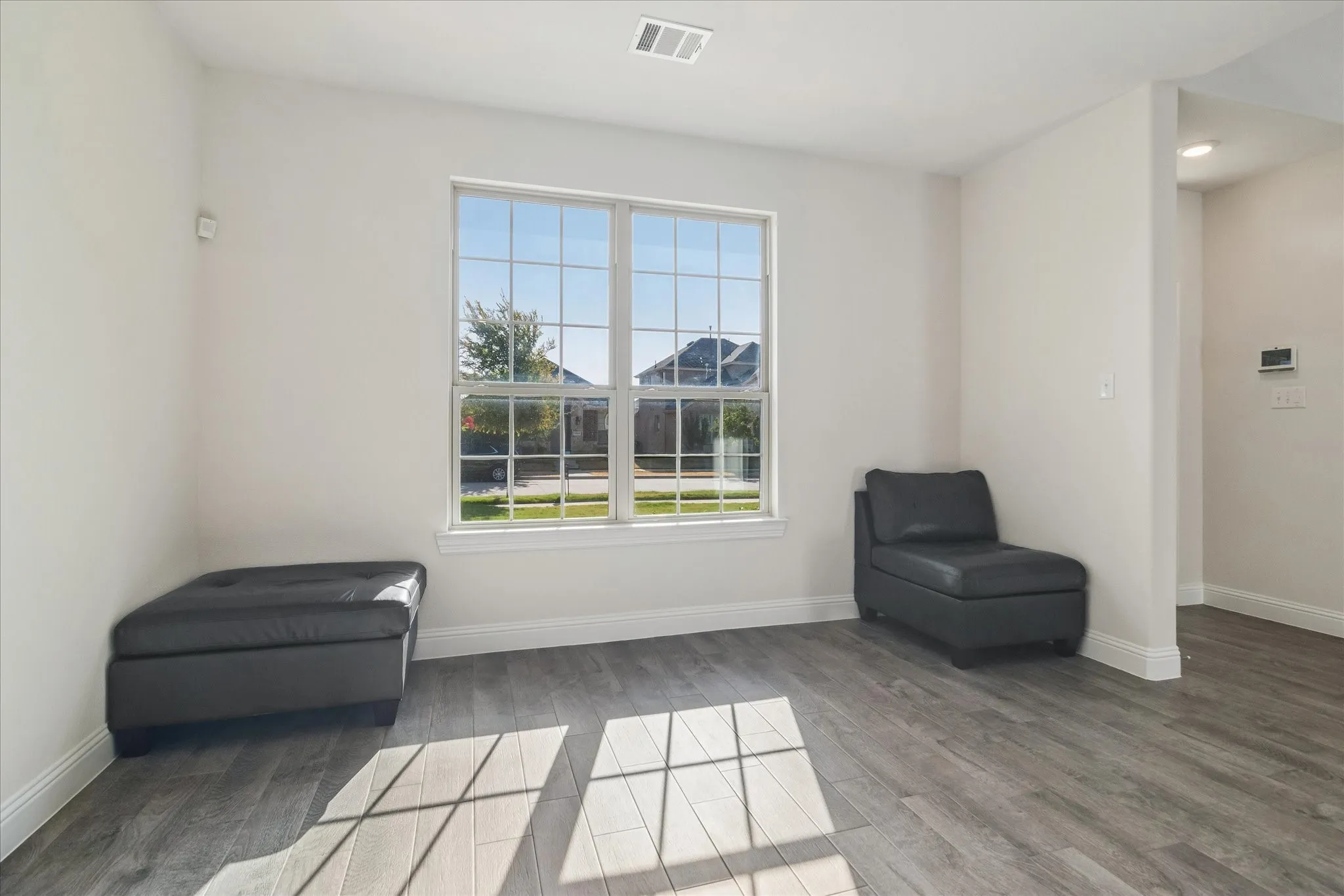 Expansive window with grid-pane design, wood-finish flooring, recessed lighting, and crisp white walls