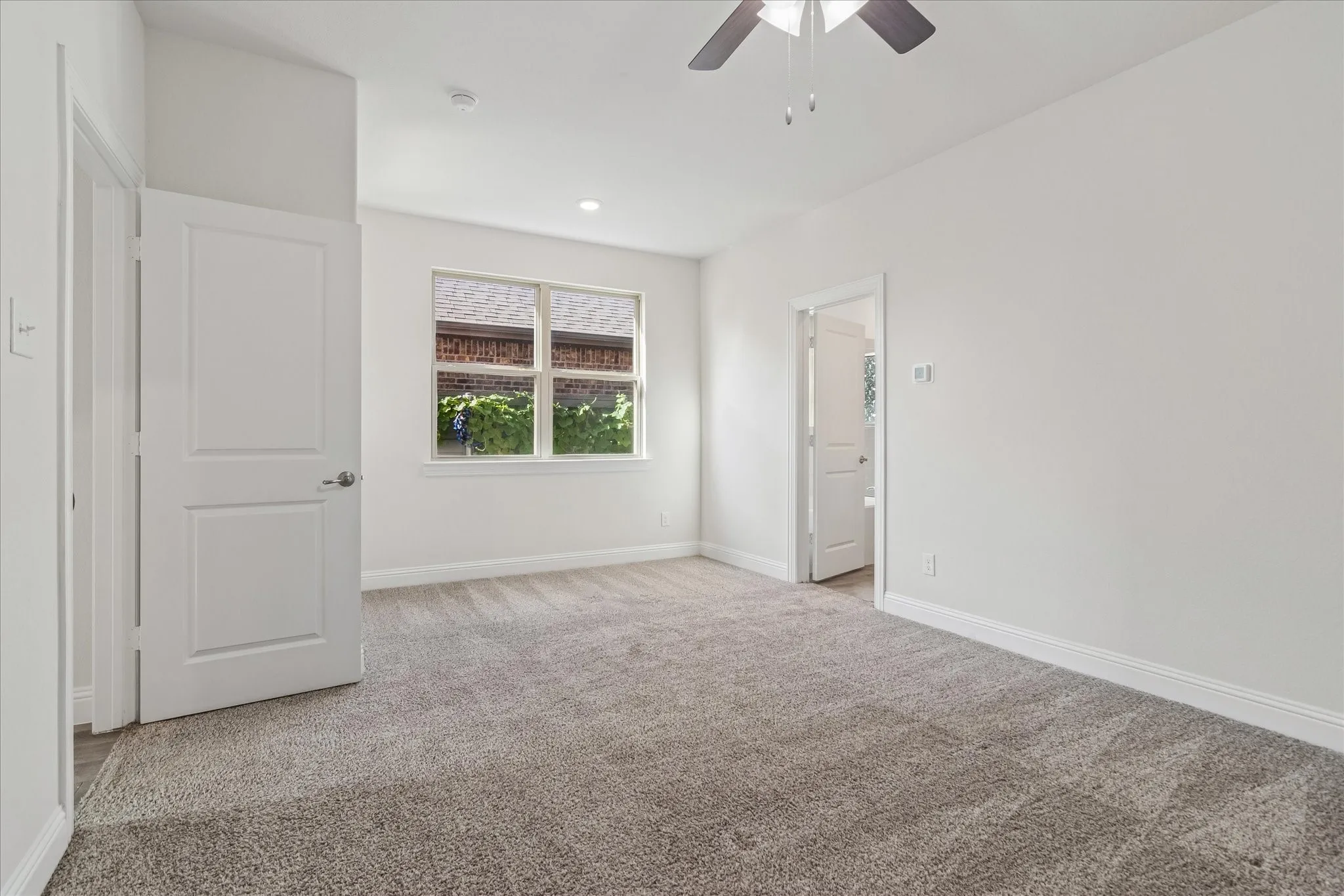 Spacious room with plush gray carpeting, white painted walls, and a ceiling fan