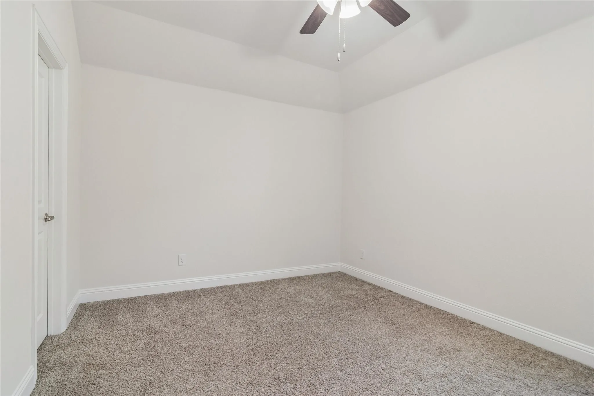 Tray ceiling with a ceiling fan, light gray carpeting, white walls, and a white door with a polished nickel knob