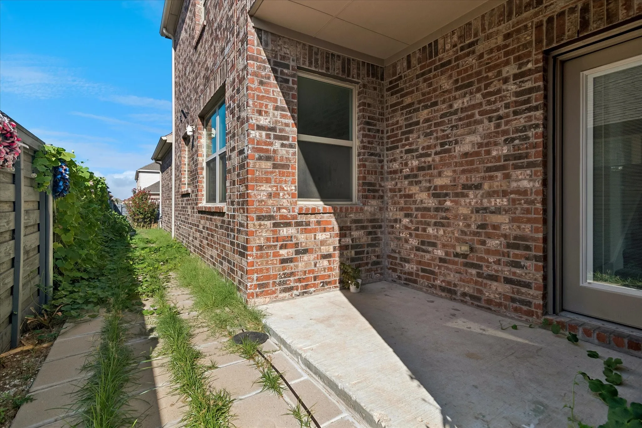 Brick exterior, covered patio, concrete patio, concrete walkway, full-light door