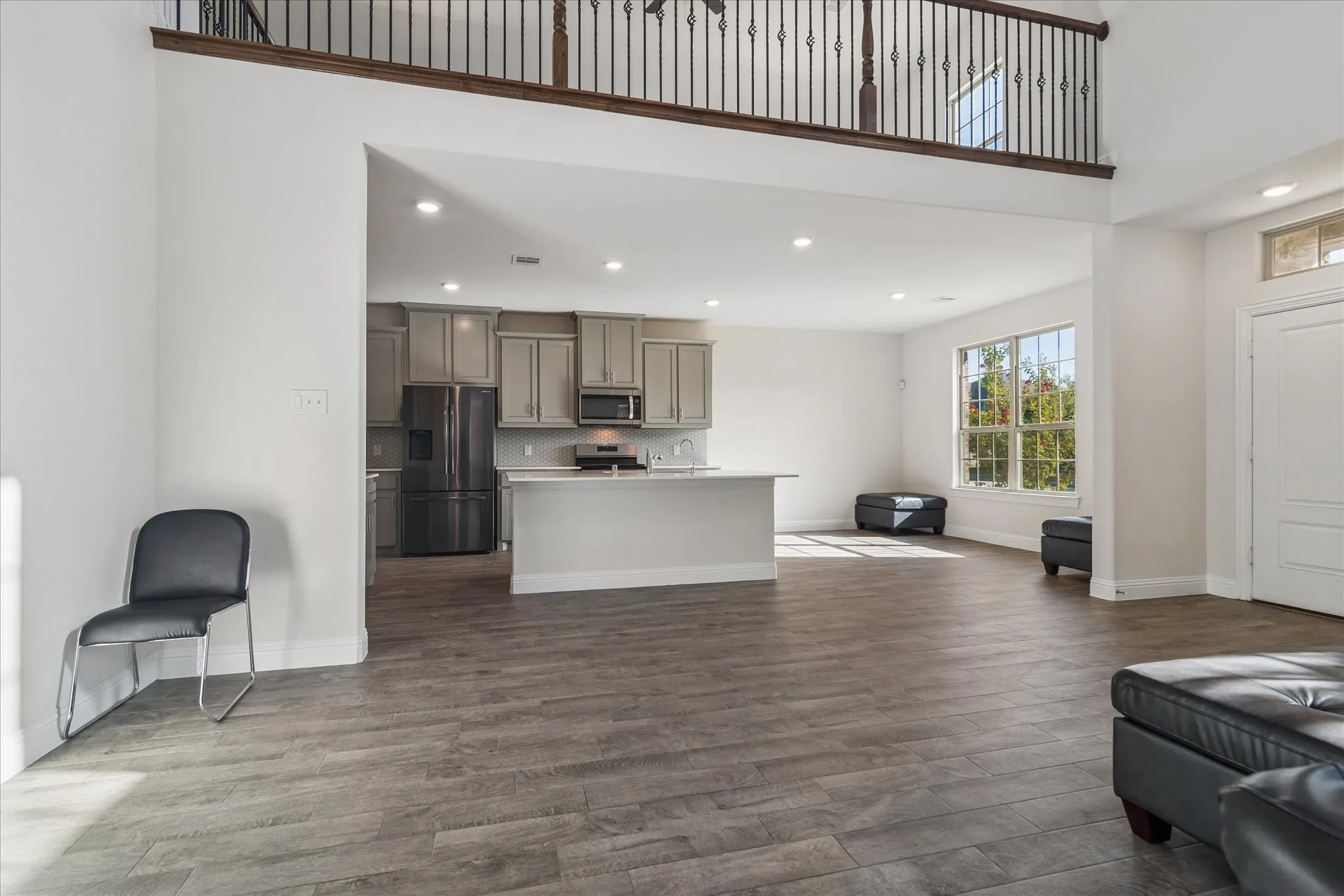 High ceilings with an open loft area, wood-finish flooring, recessed lighting, and large windows