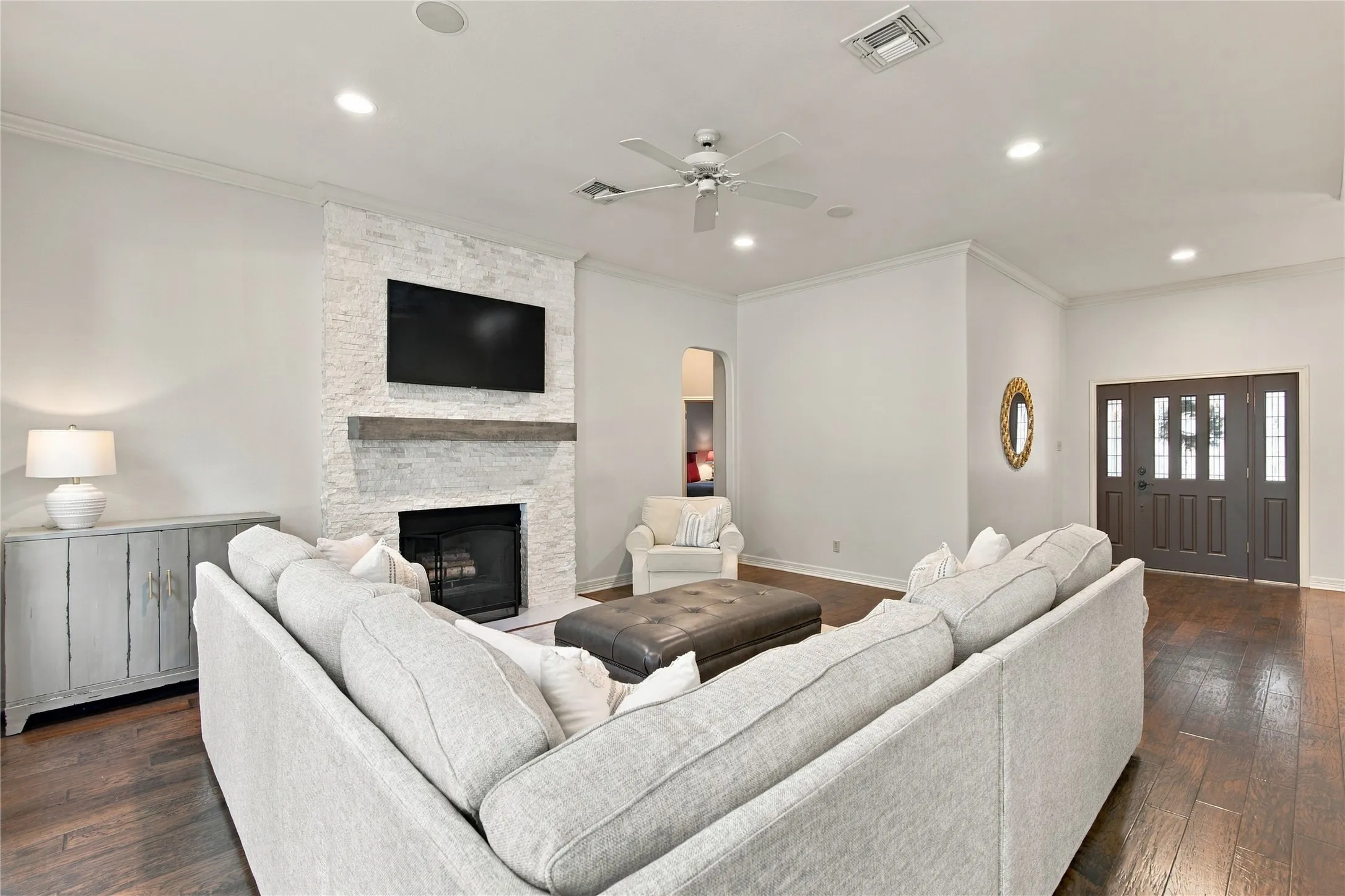 Wood-finish flooring, recessed lighting, and a stacked stone fireplace with a substantial wood mantel