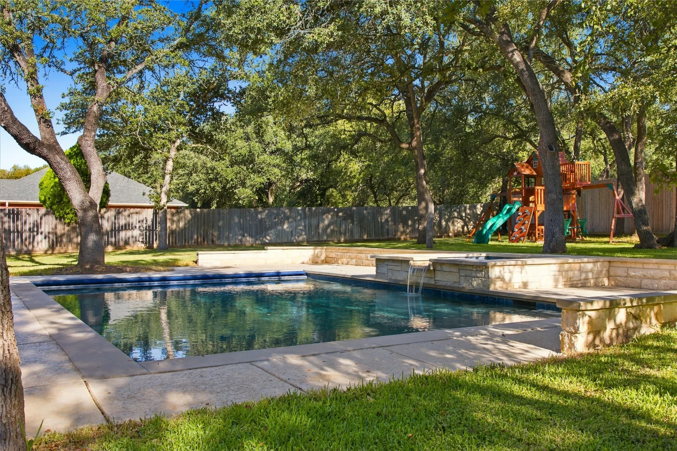 Rectangular swimming pool with integrated spa and stone surround