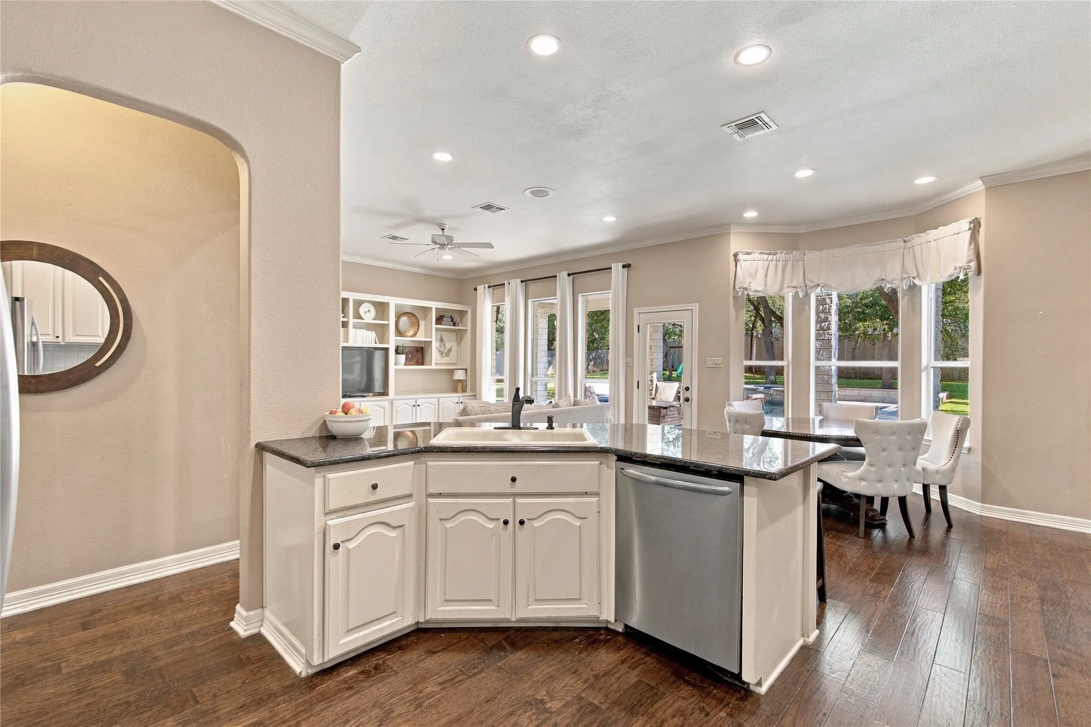 Kitchen island with an undermount sink, a stainless steel dishwasher, and a dark stone countertop
