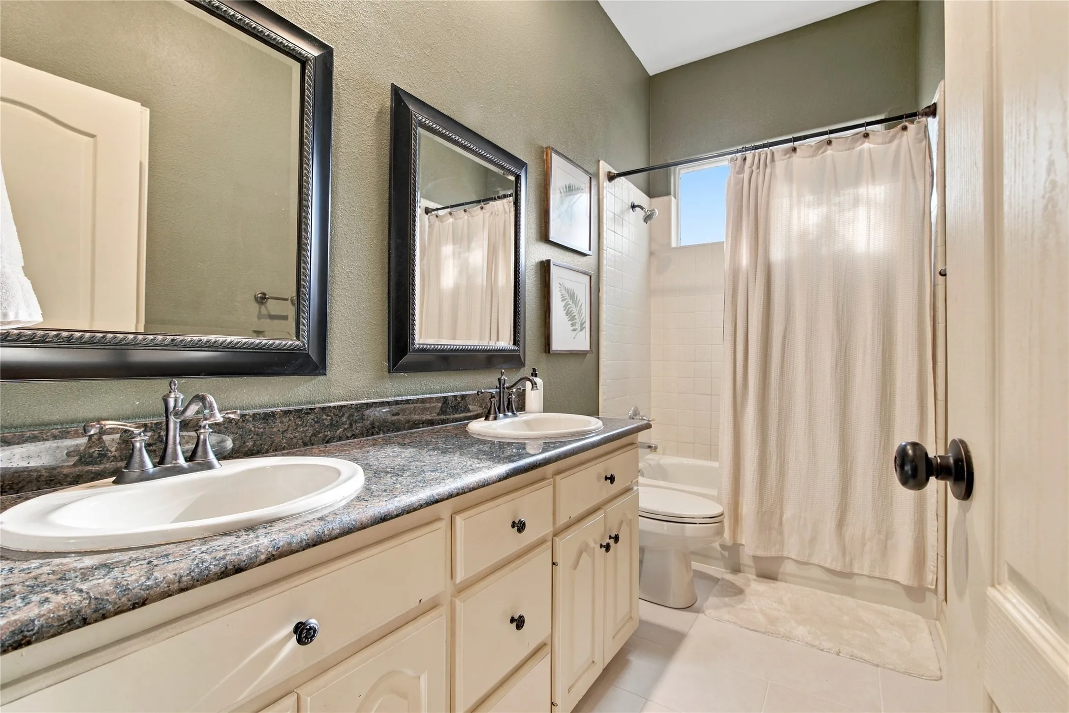 Dual vanity with undermount sinks, speckled countertop, and light-toned cabinetry