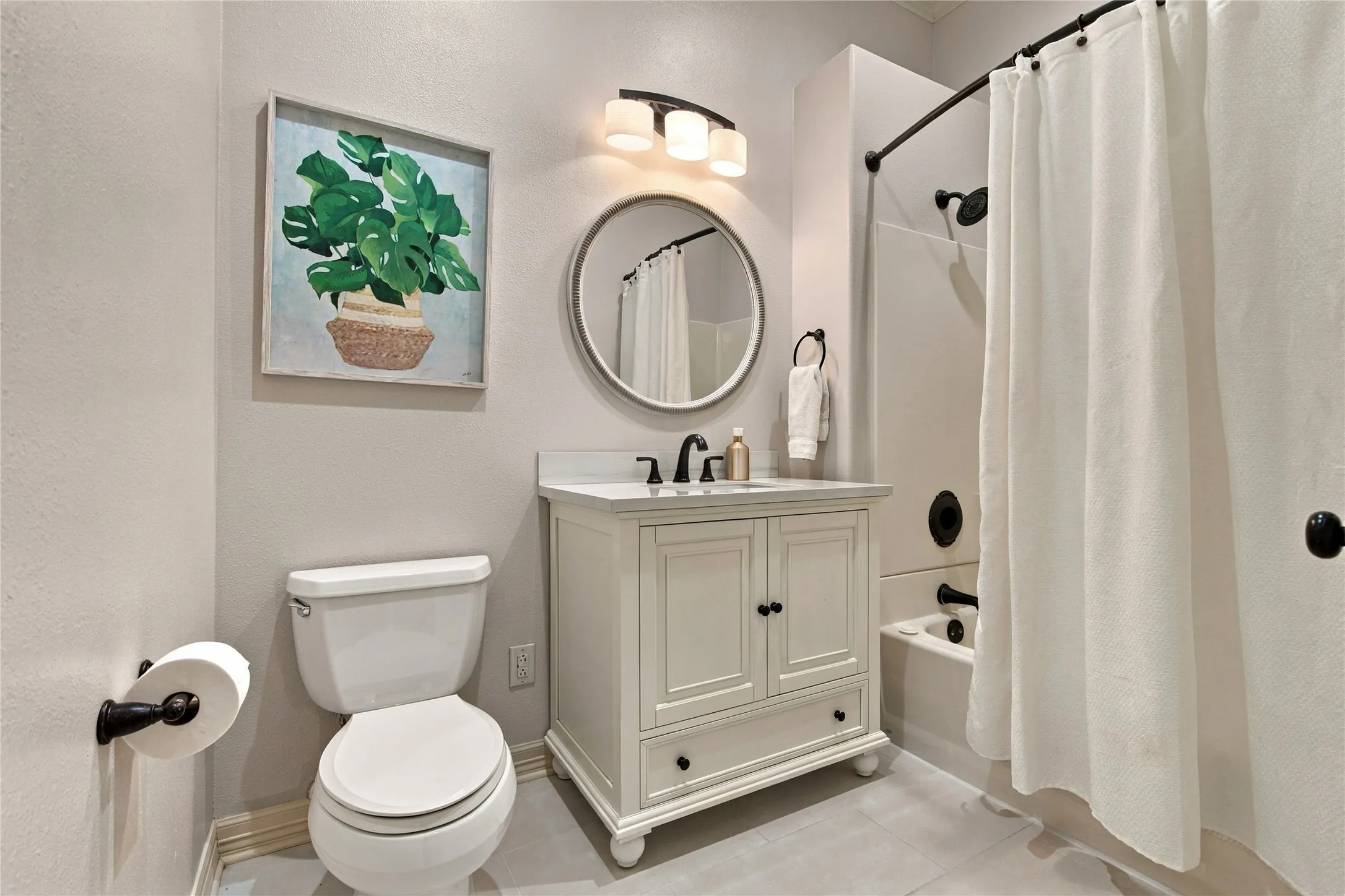 White vanity with a single basin sink, matte black faucet, and round mirror