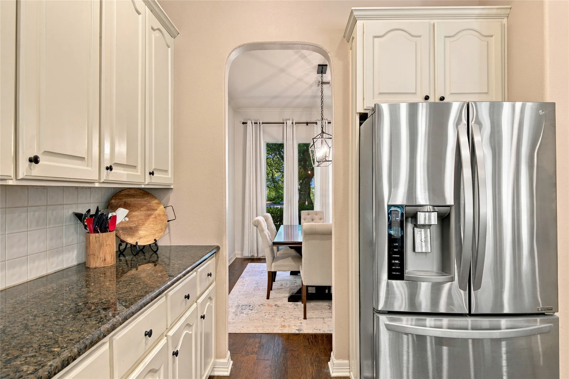 Kitchen featuring white cabinetry, dark countertops, and a stainless steel refrigerator