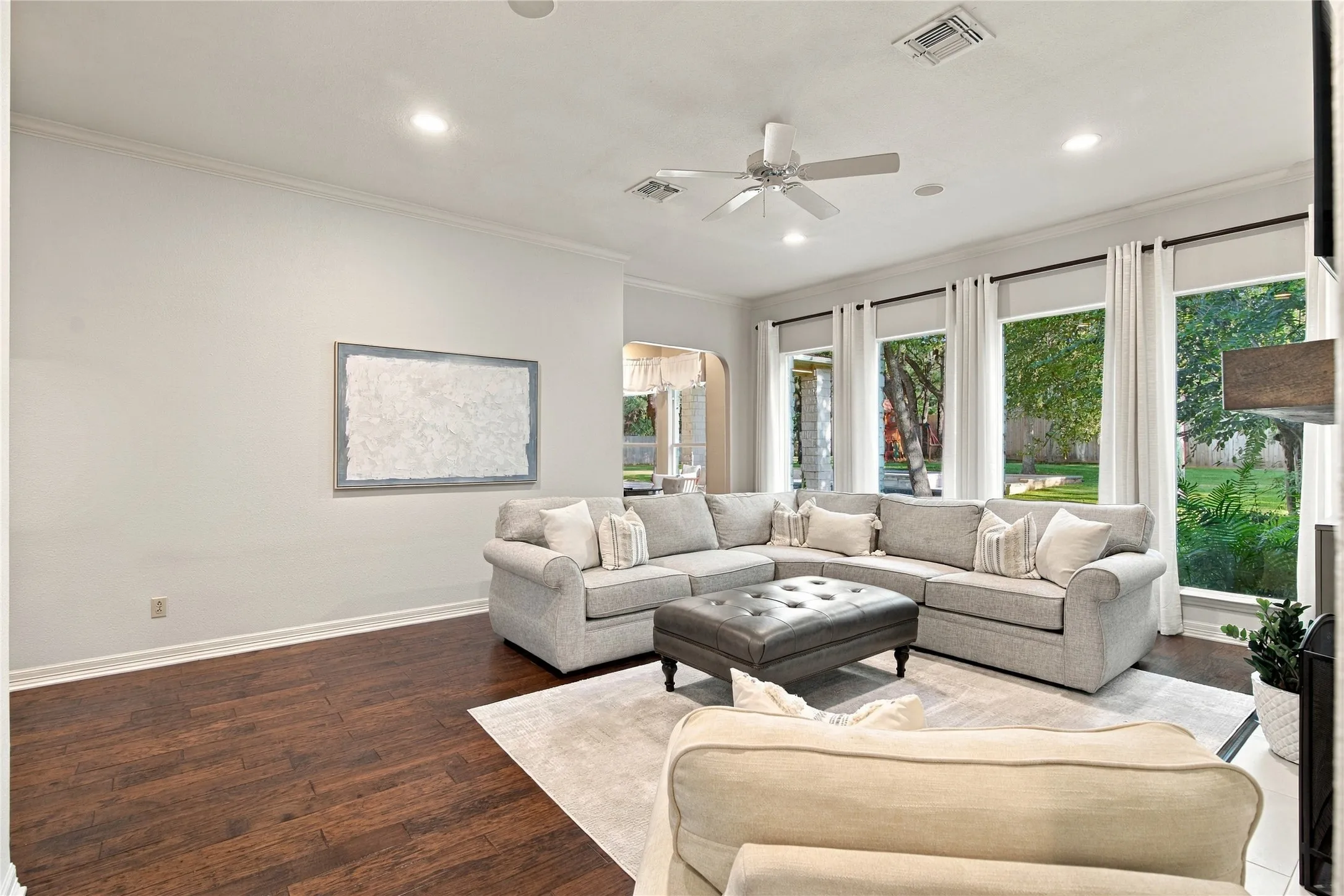 Recessed lighting, crown molding, wood-finish flooring, ceiling fan, and multiple large windows