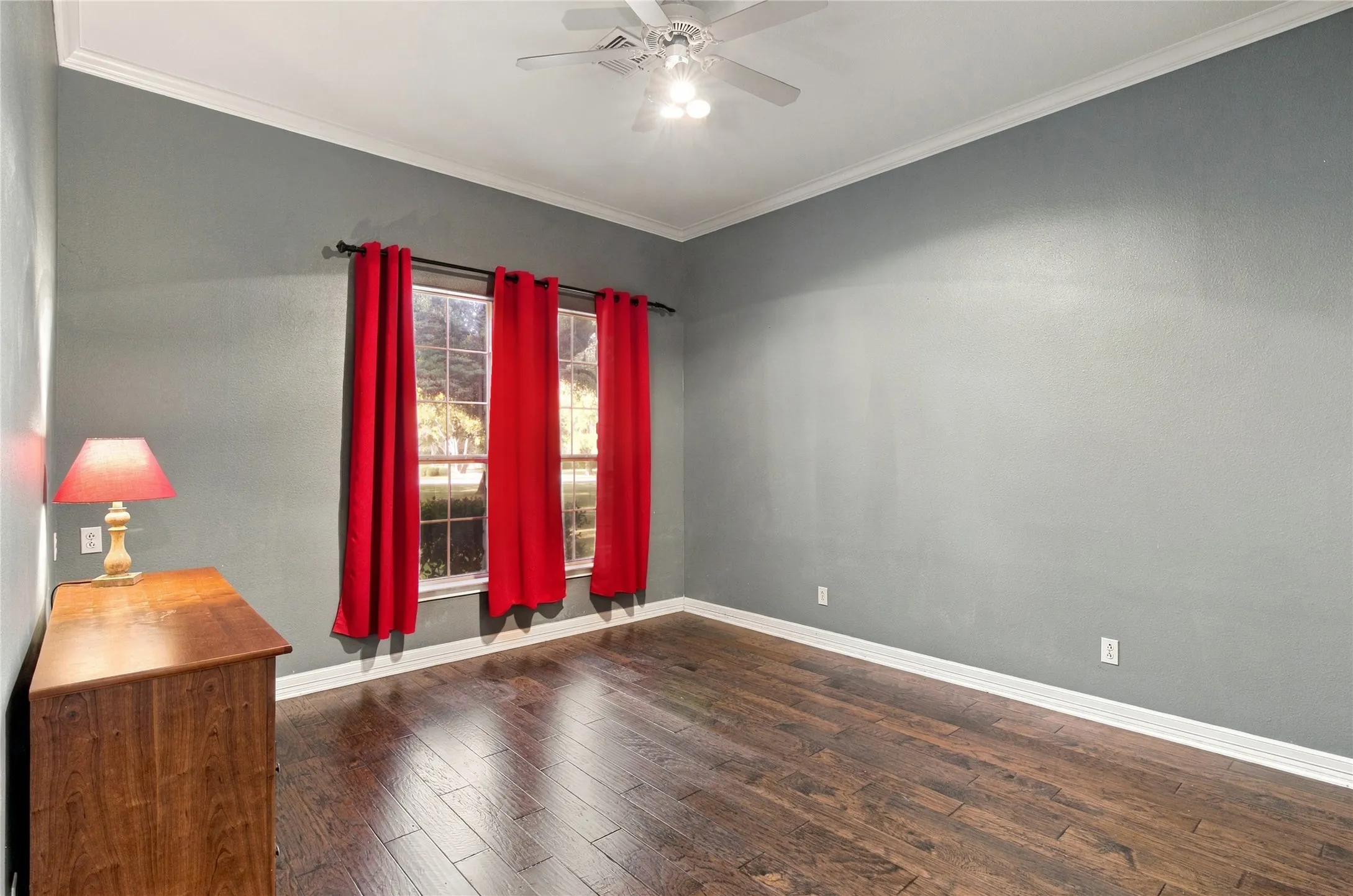 Crown molding, rich wood-finish flooring, and a ceiling fan with integrated lighting