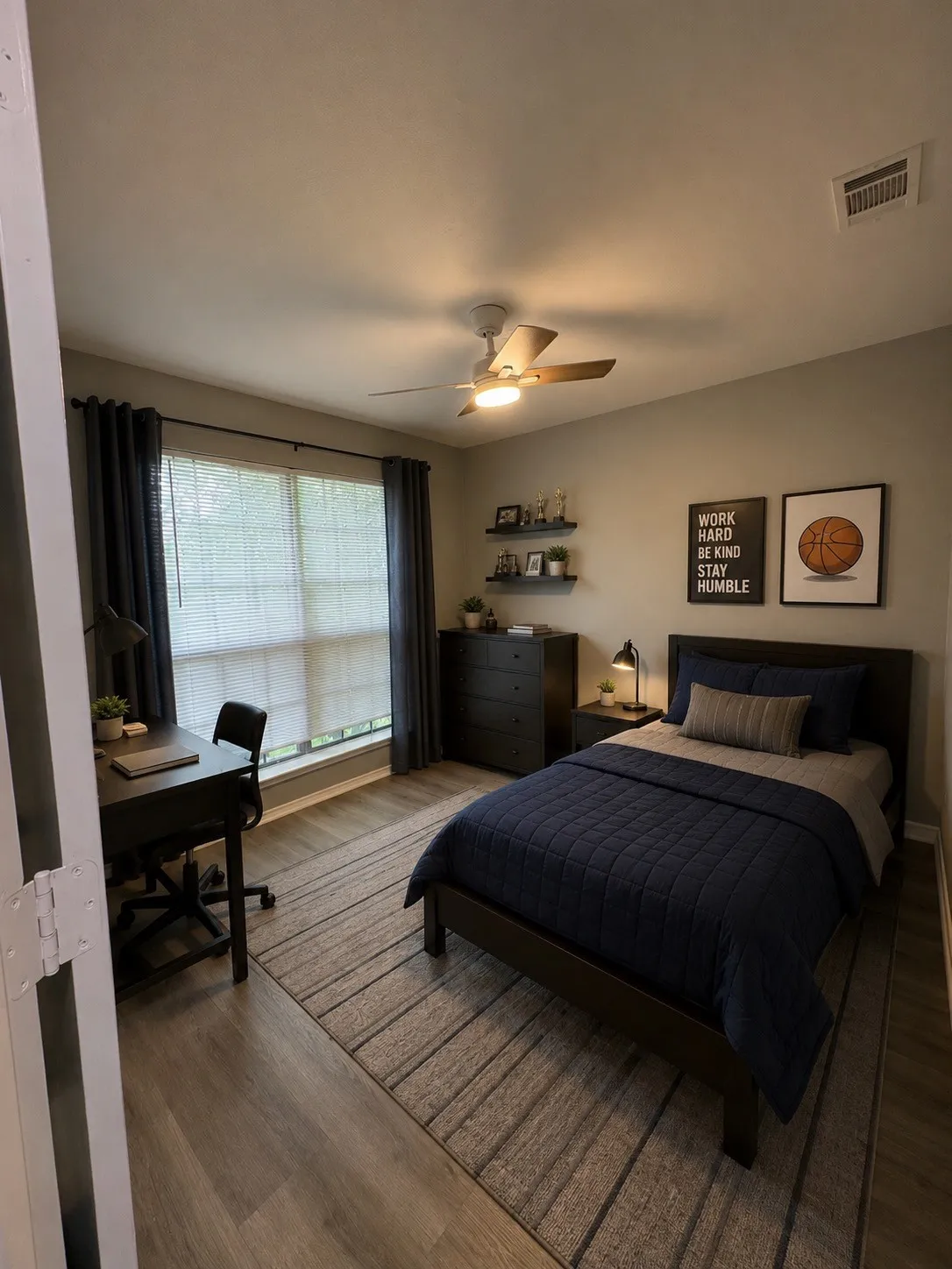 Wood-finish flooring, ceiling fan with integrated lighting, window with blinds, dark window treatments, and built-in wall shelving