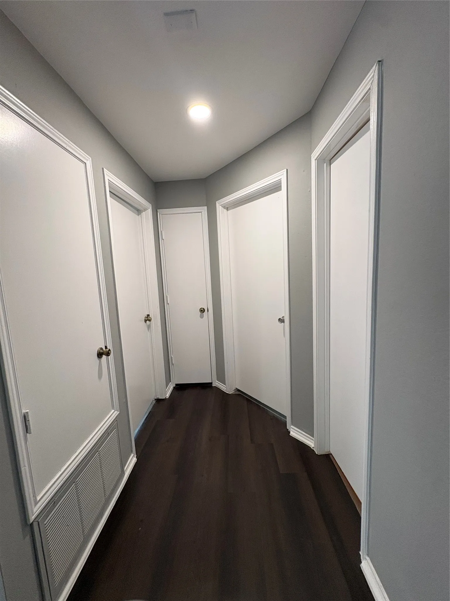 Wood-finish flooring with crisp white trim, recessed lighting, and bright white doors