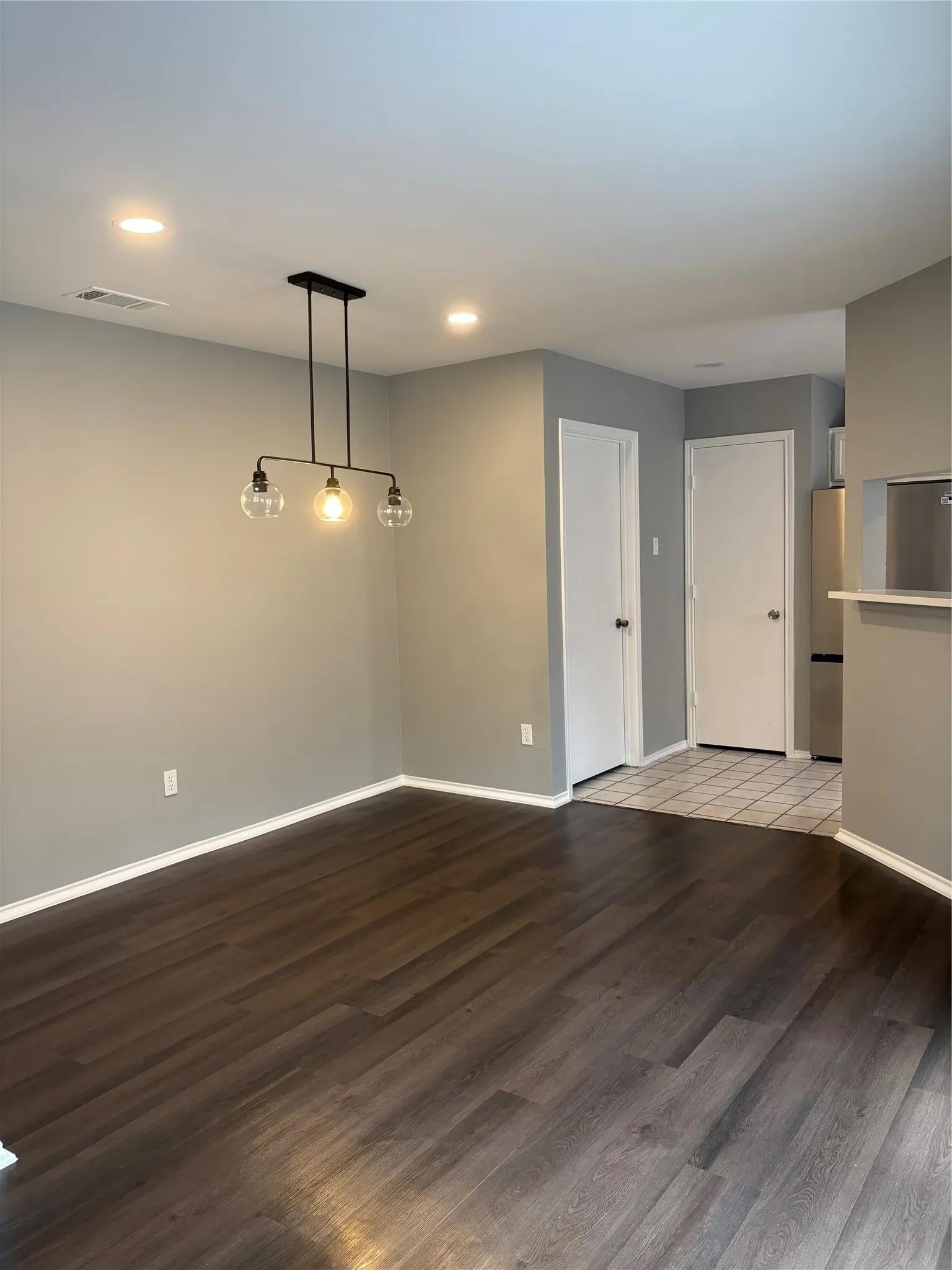 Recessed ceiling lighting, wood-finish flooring, modern linear chandelier, neutral wall tones, and white interior doors
